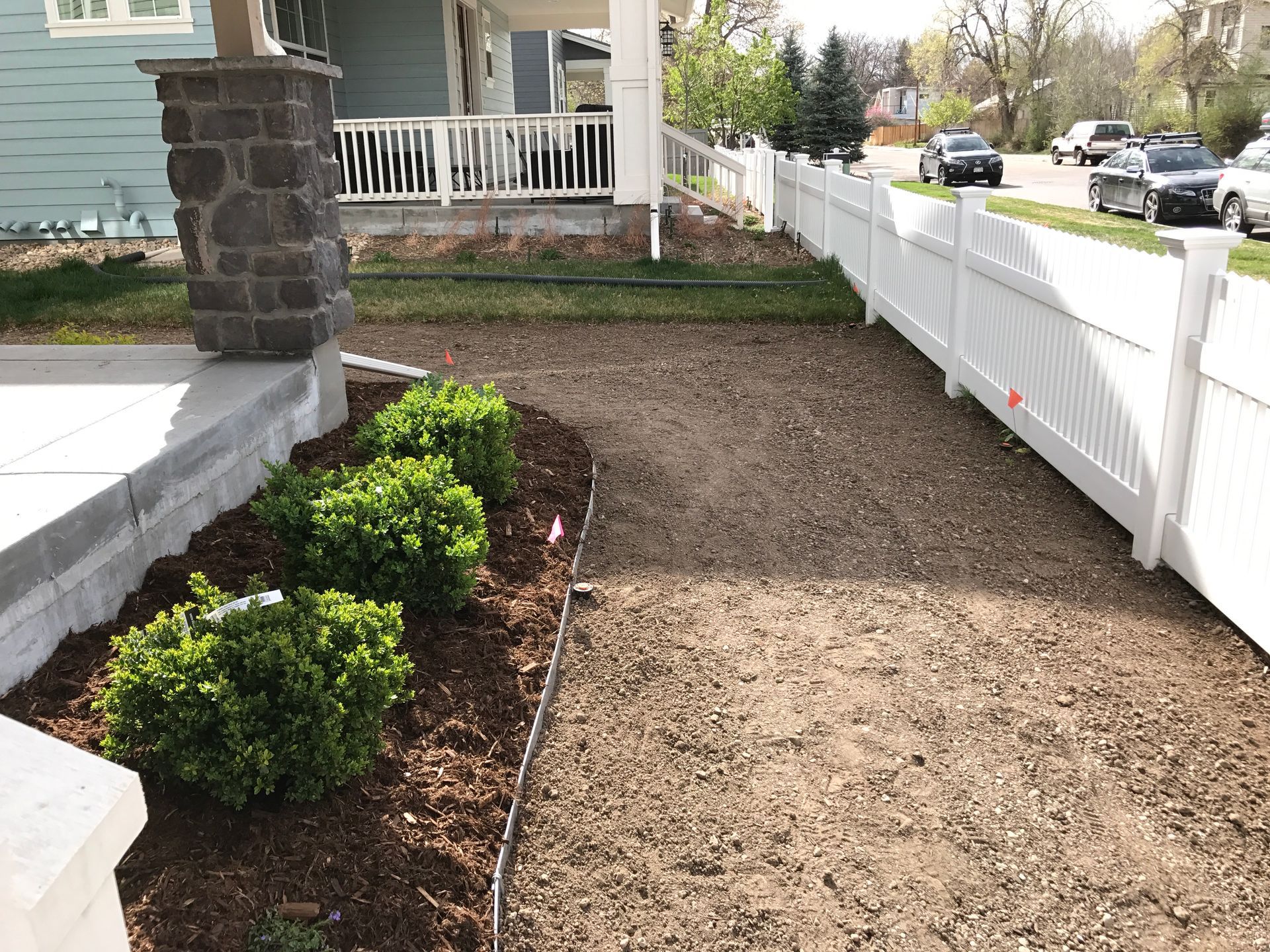 View of a walkway bordered by a white fence and garden beds.