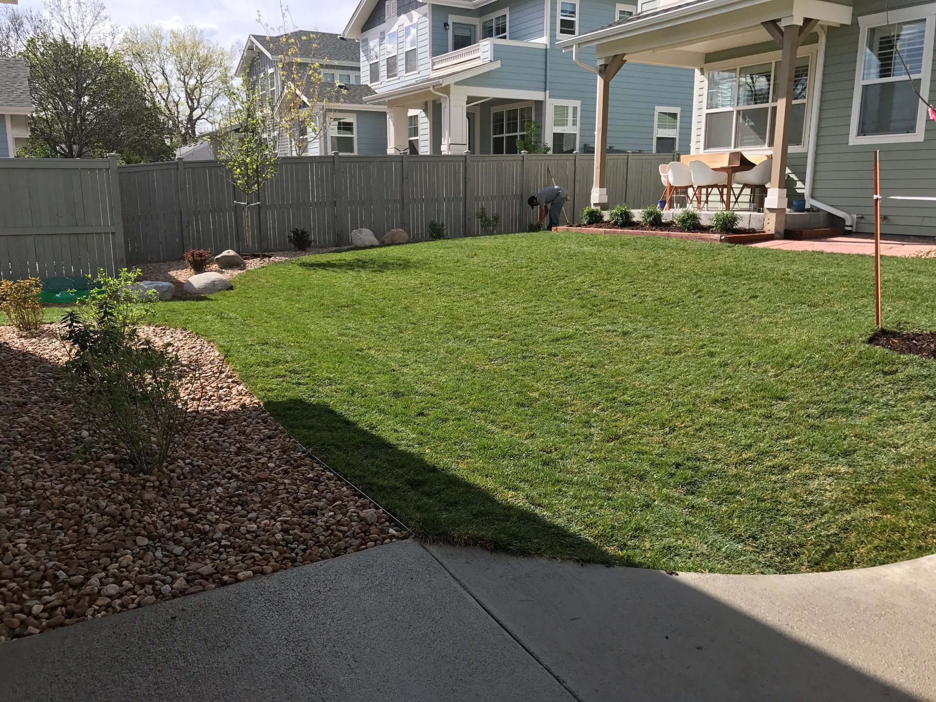 Lawn with brown mulch border, wooden fence, and light blue houses.