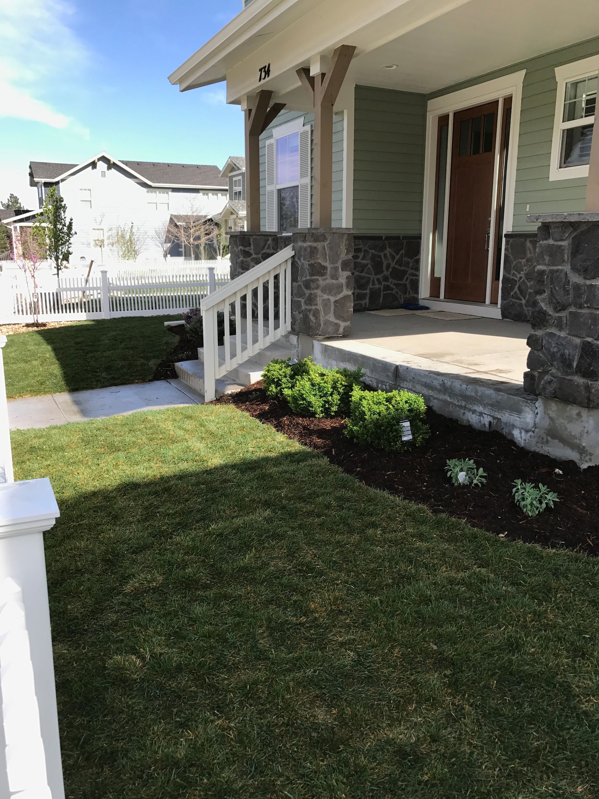 Green house exterior with manicured lawn and stone accents.