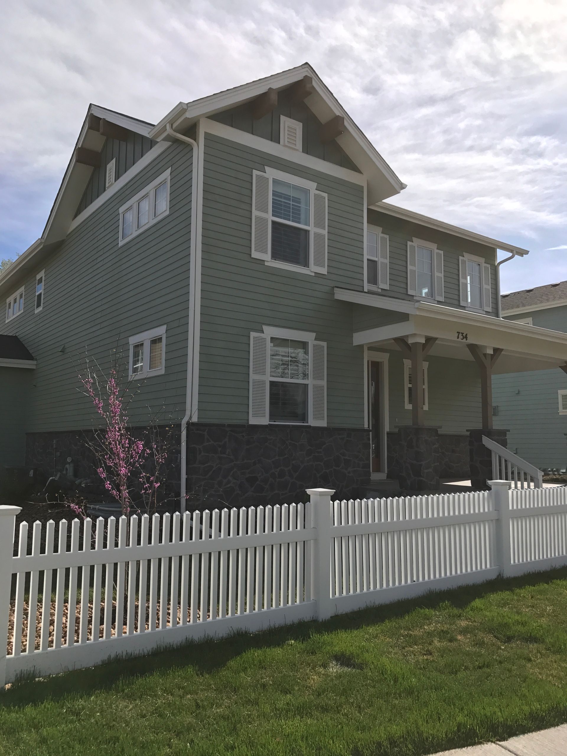 Two-story house with green siding, white trim, and a picket fence.
