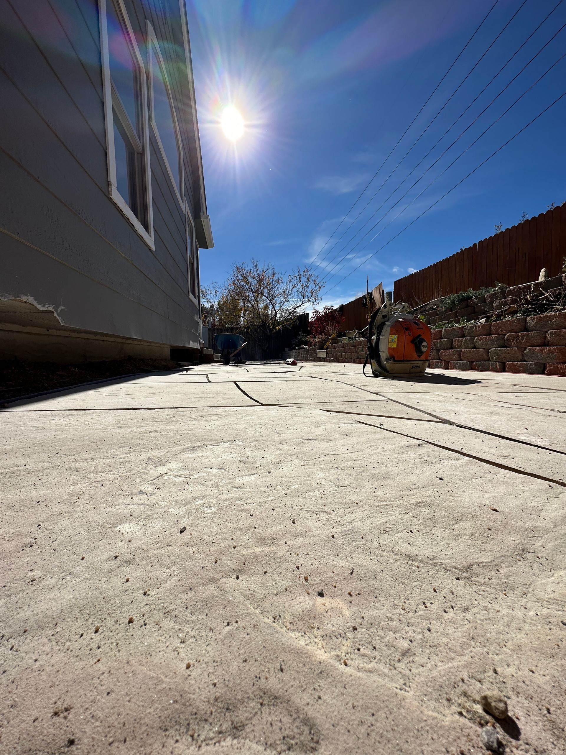 Concrete surface with a building on the left and construction work visible in the middle distance under a sunny sky.