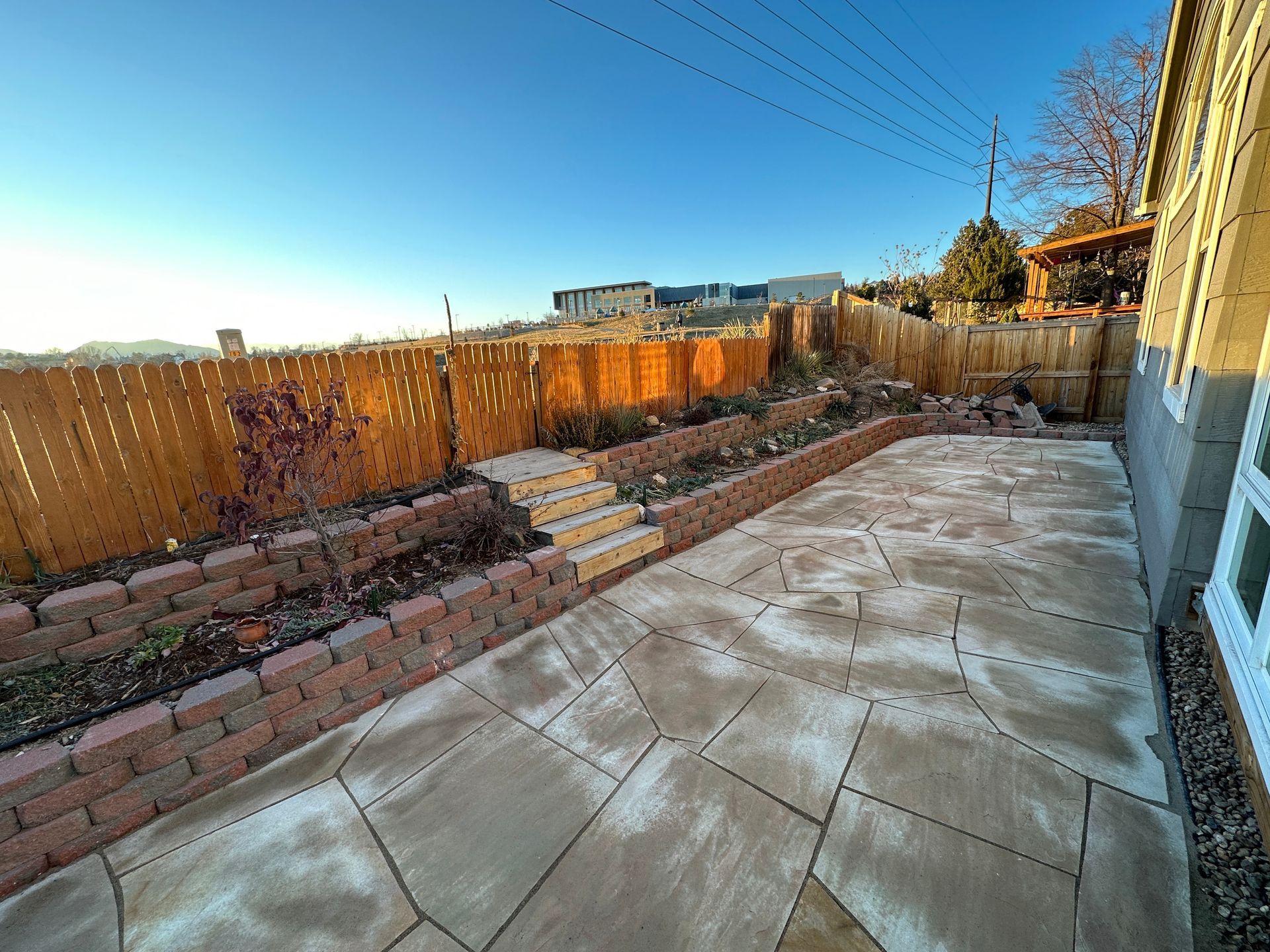 Backyard patio with brick retaining walls, wooden fence, and stone paving.