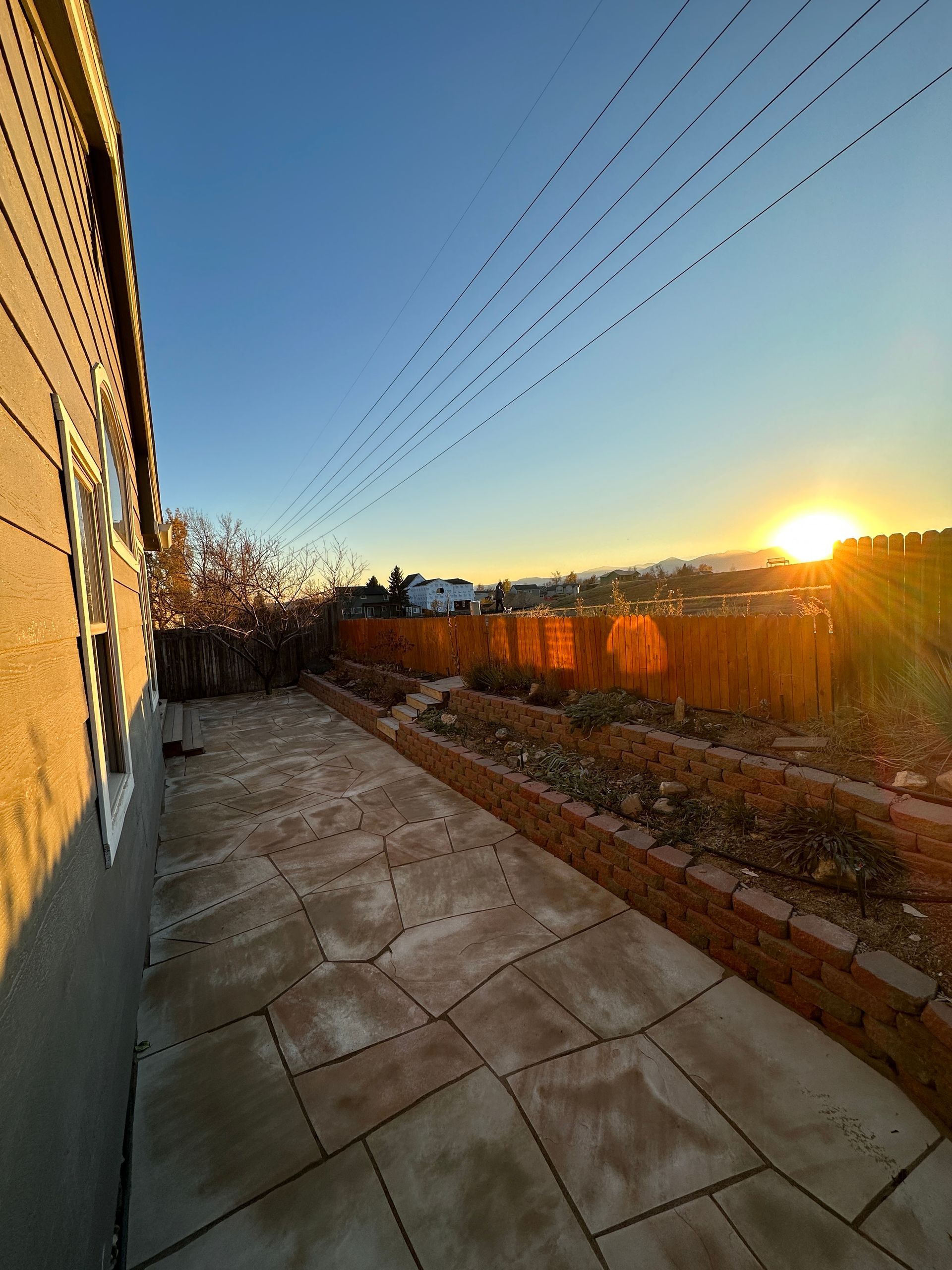 Patio with brick-lined garden beds at sunset, casting golden light.