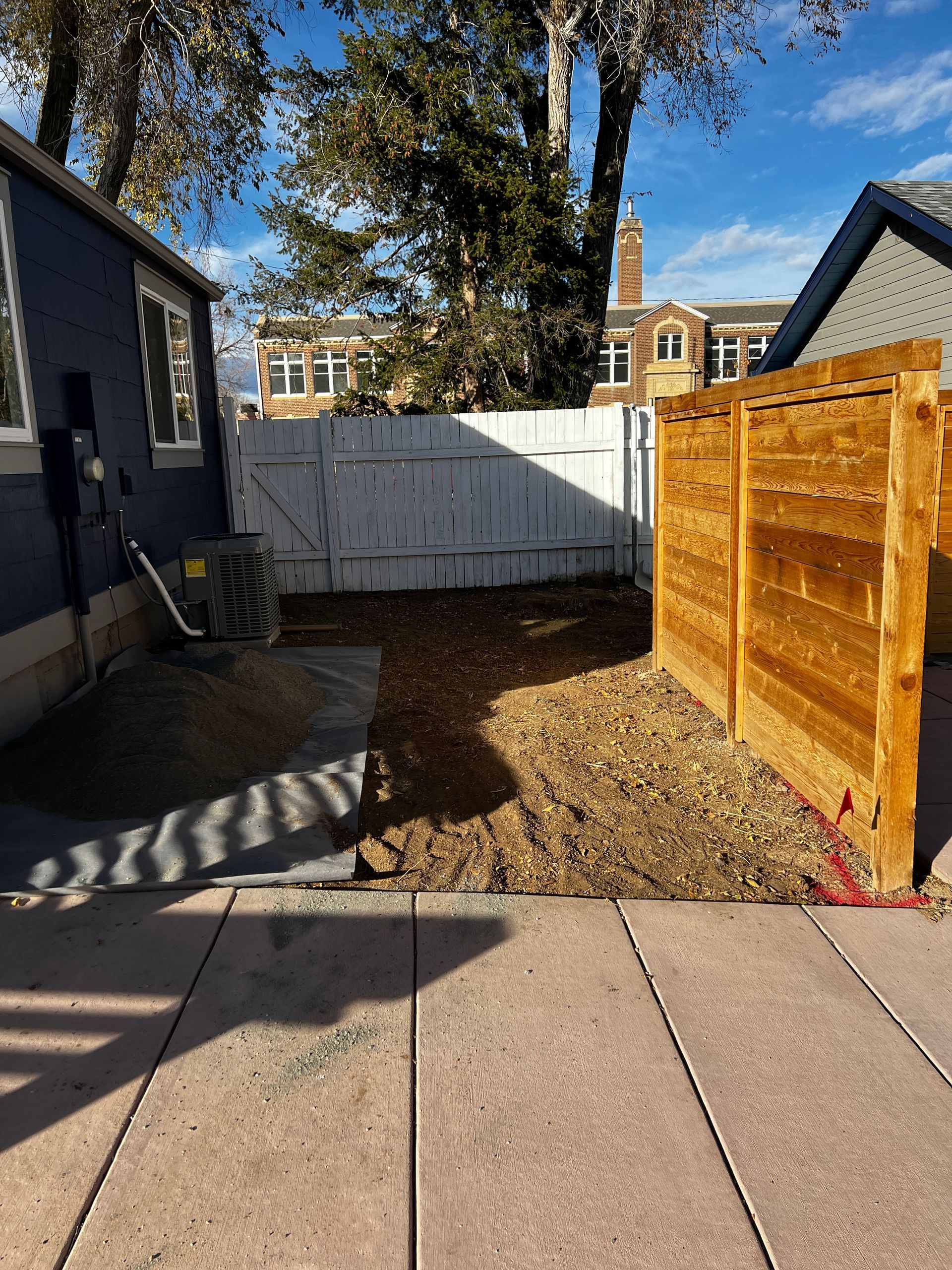 Backyard with wooden fences, gravel, and a small shed on a sunny day.