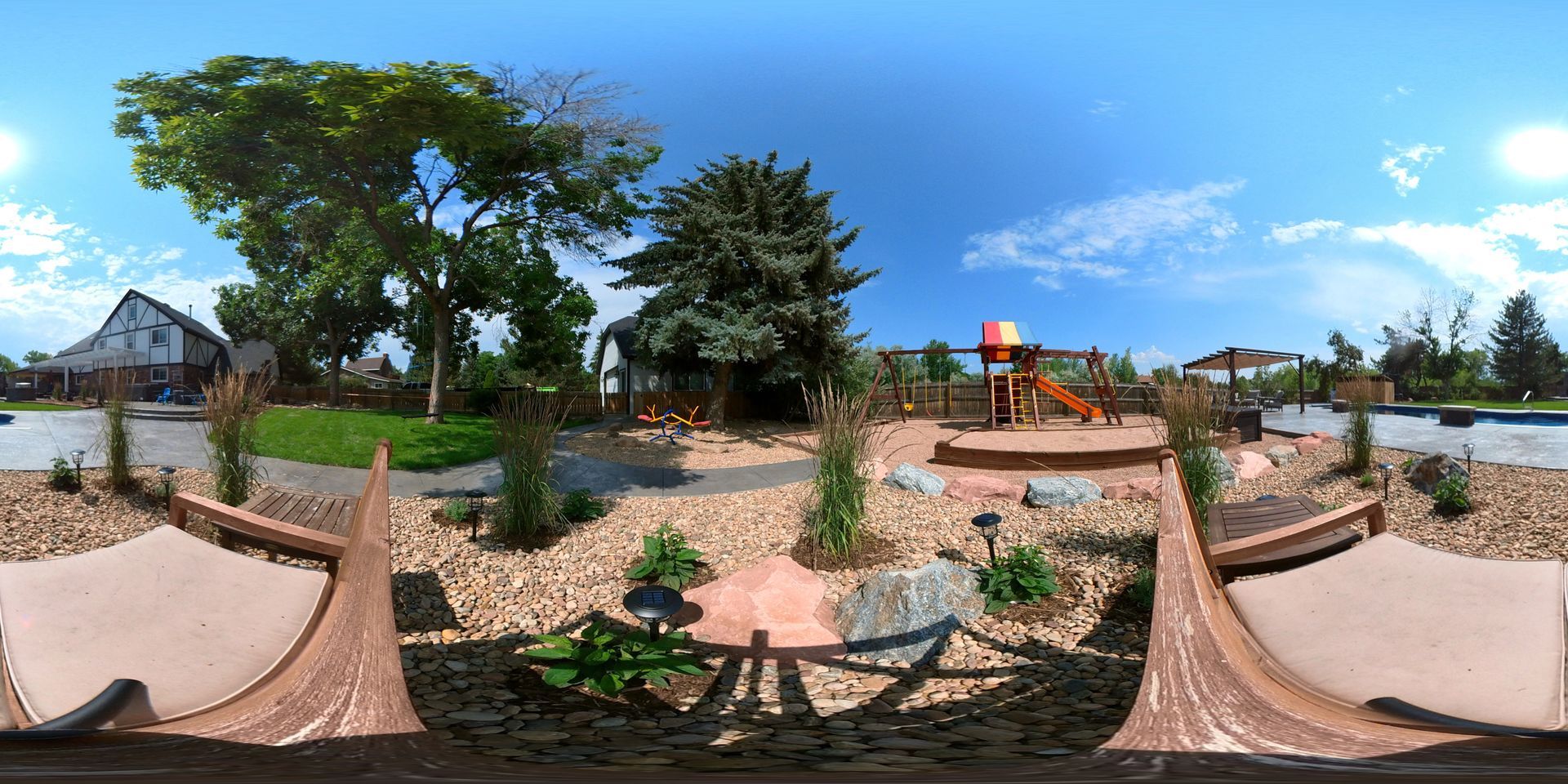 Playground with trees, blue sky, and a wooden bridge.
