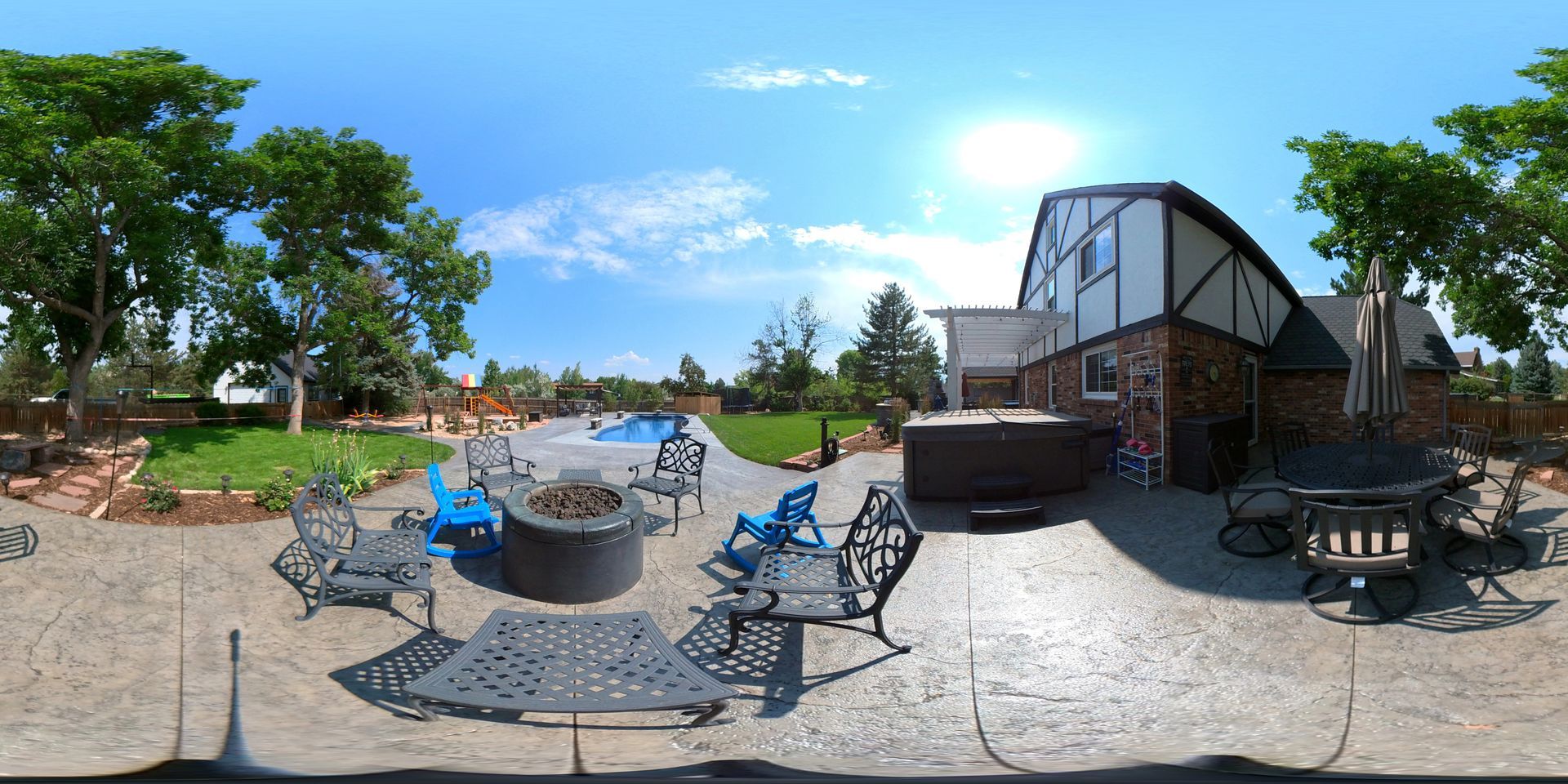 Backyard with pool, hot tub, and patio furniture on a sunny day. A house is visible in the background.