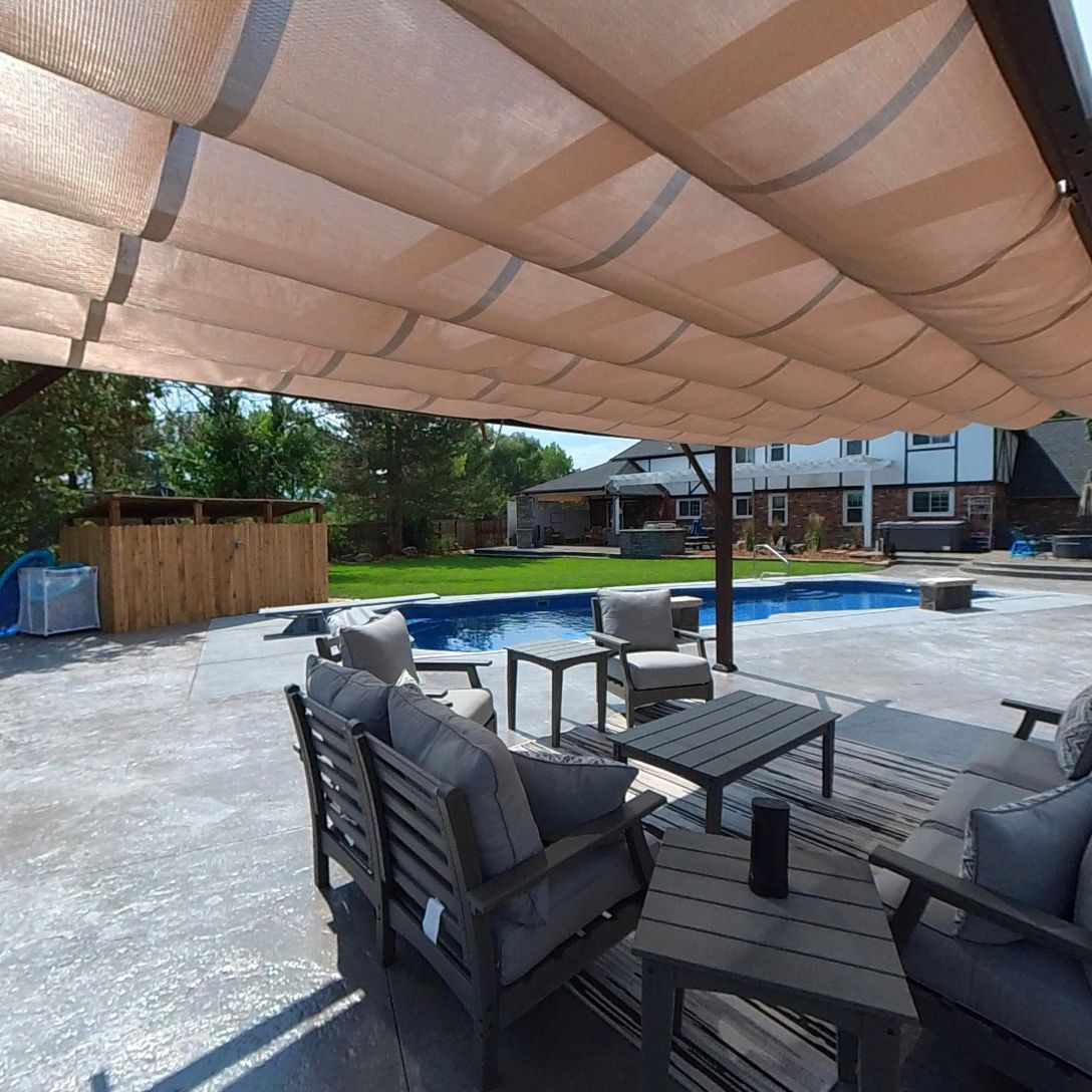 Patio with furniture, a pool, and a canopy. Gray couches and tables on a concrete patio.