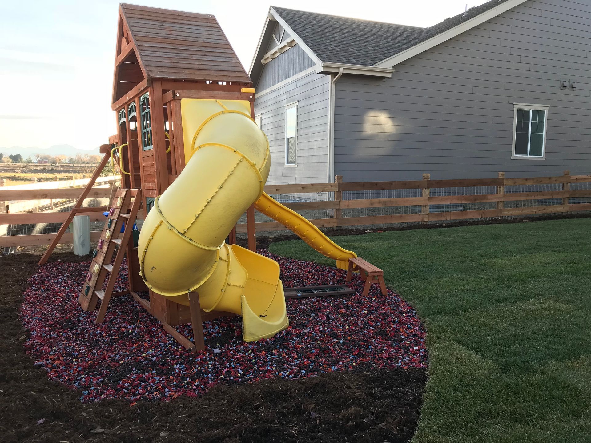 Play set with yellow slide and wooden structure in a yard.