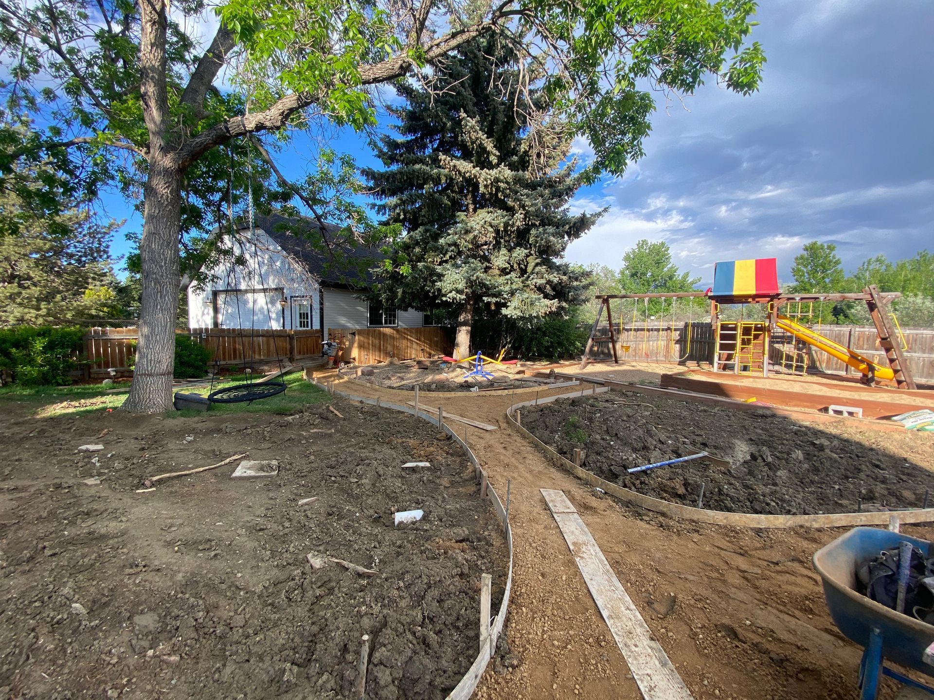 Backyard with dirt pathways, garden beds, playground, and house.