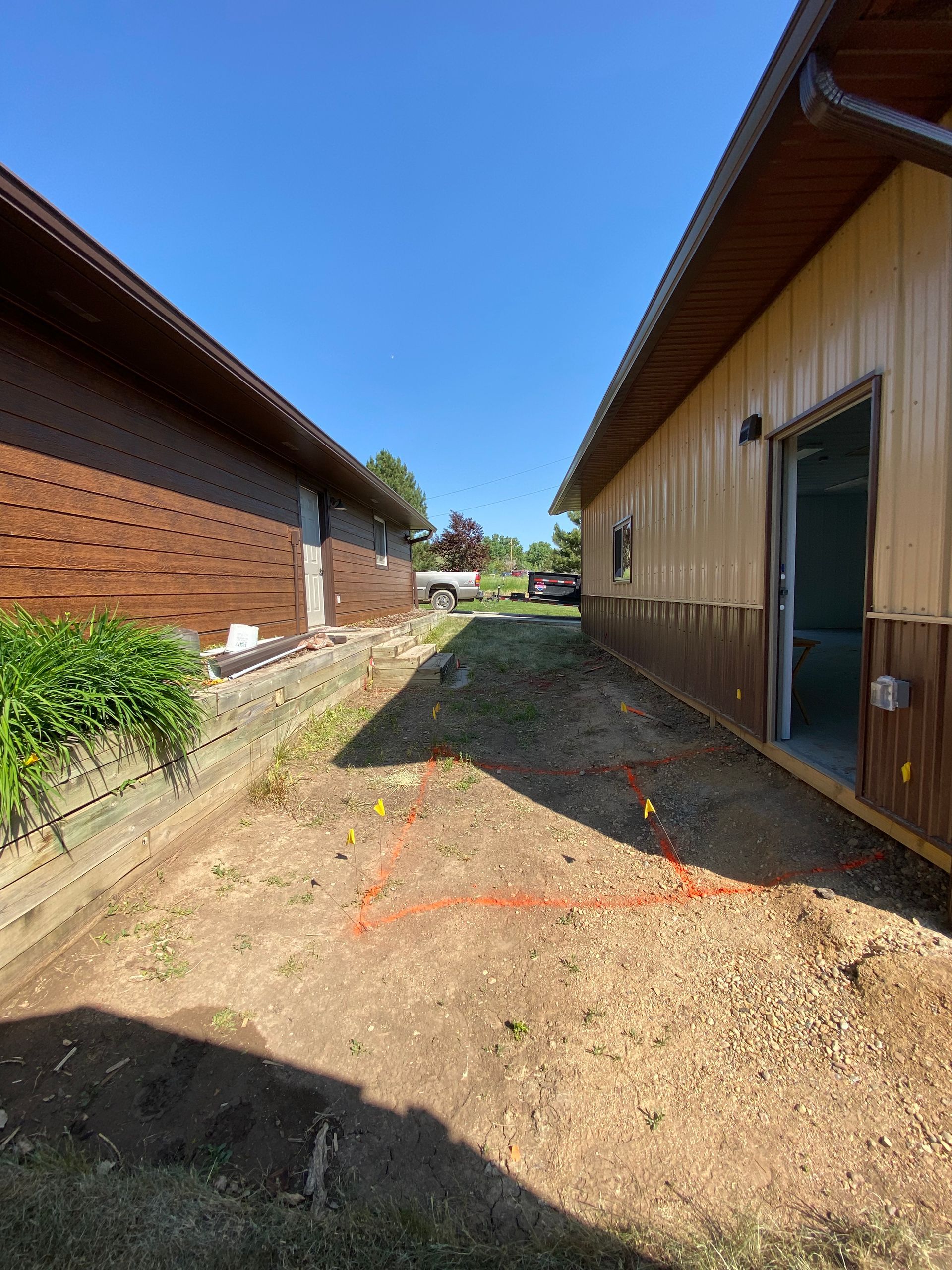 Dirt path between two buildings, orange line on ground, sunny day.