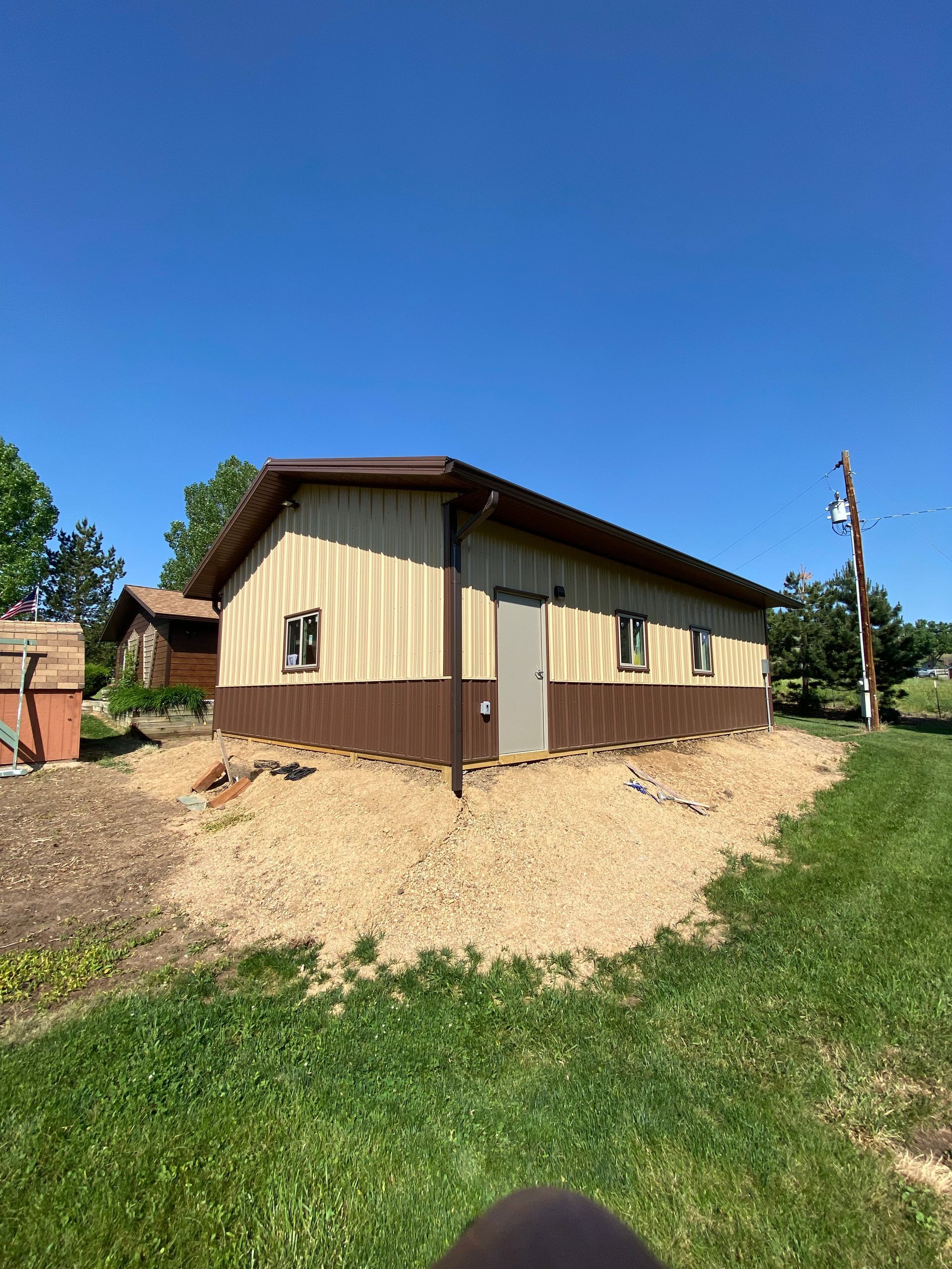 Brown and beige metal building with a dark brown trim and roof, on a sunny day.