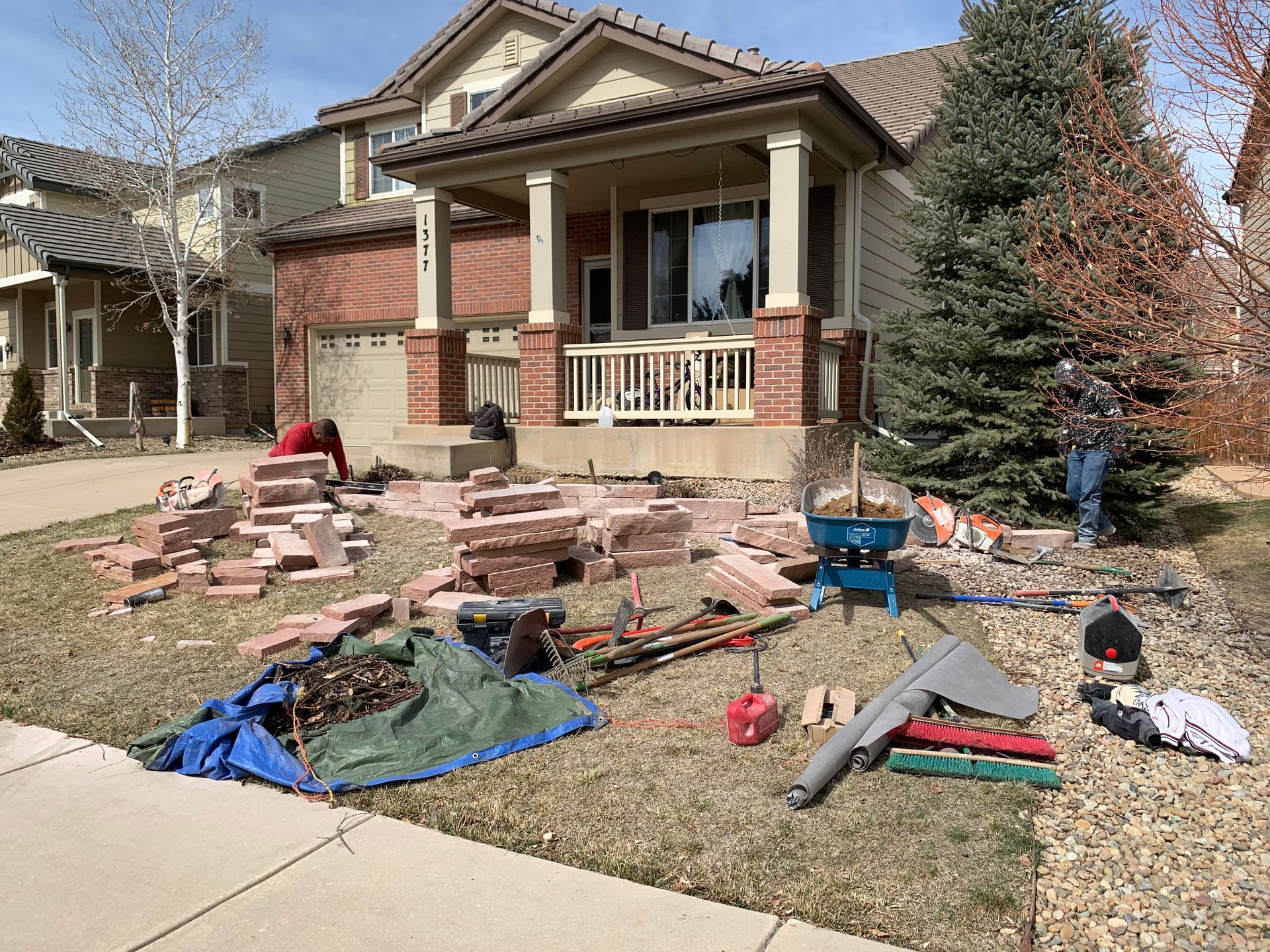 Home exterior under construction; brickwork, tools, workers.