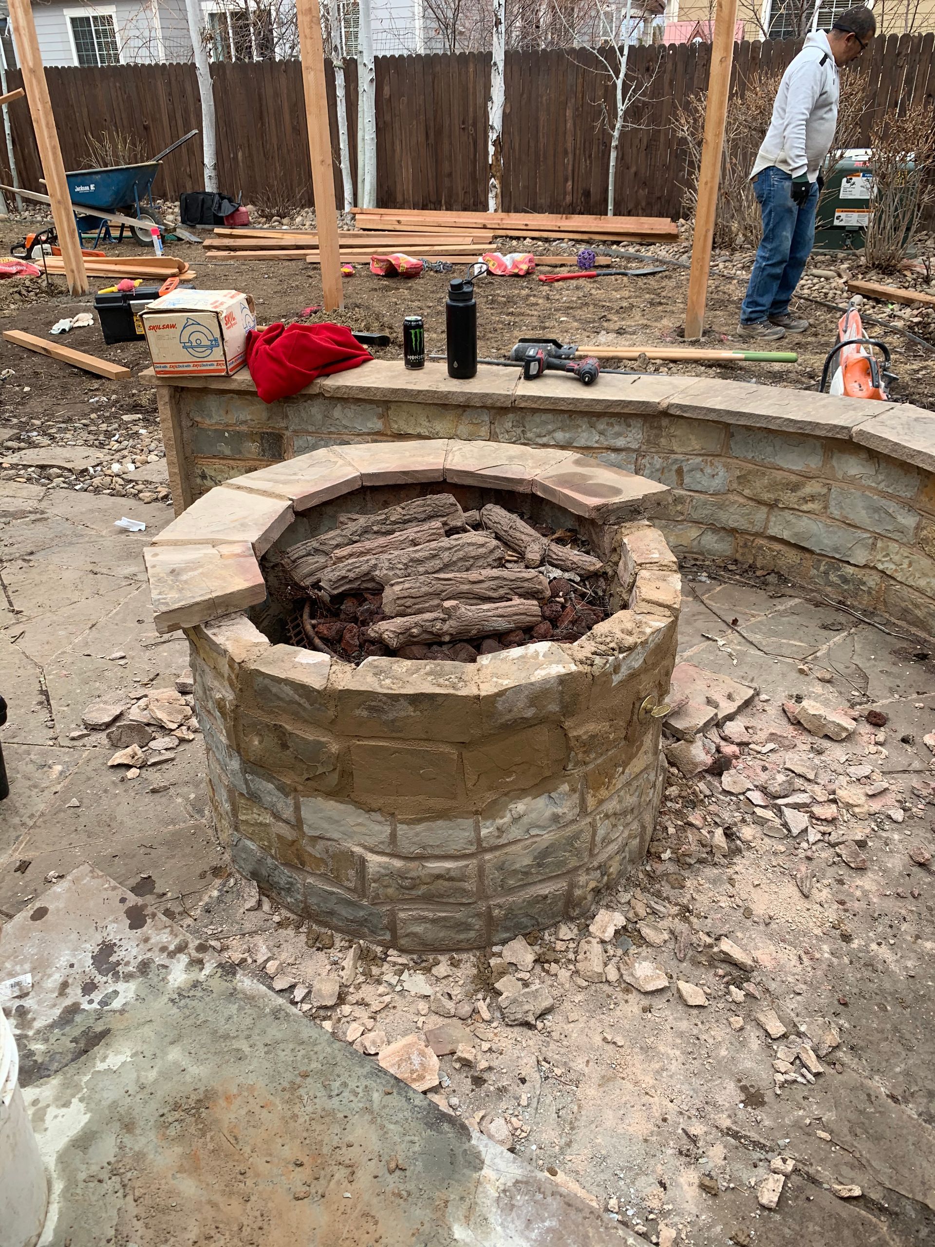 Stone fire pit under construction; person nearby.