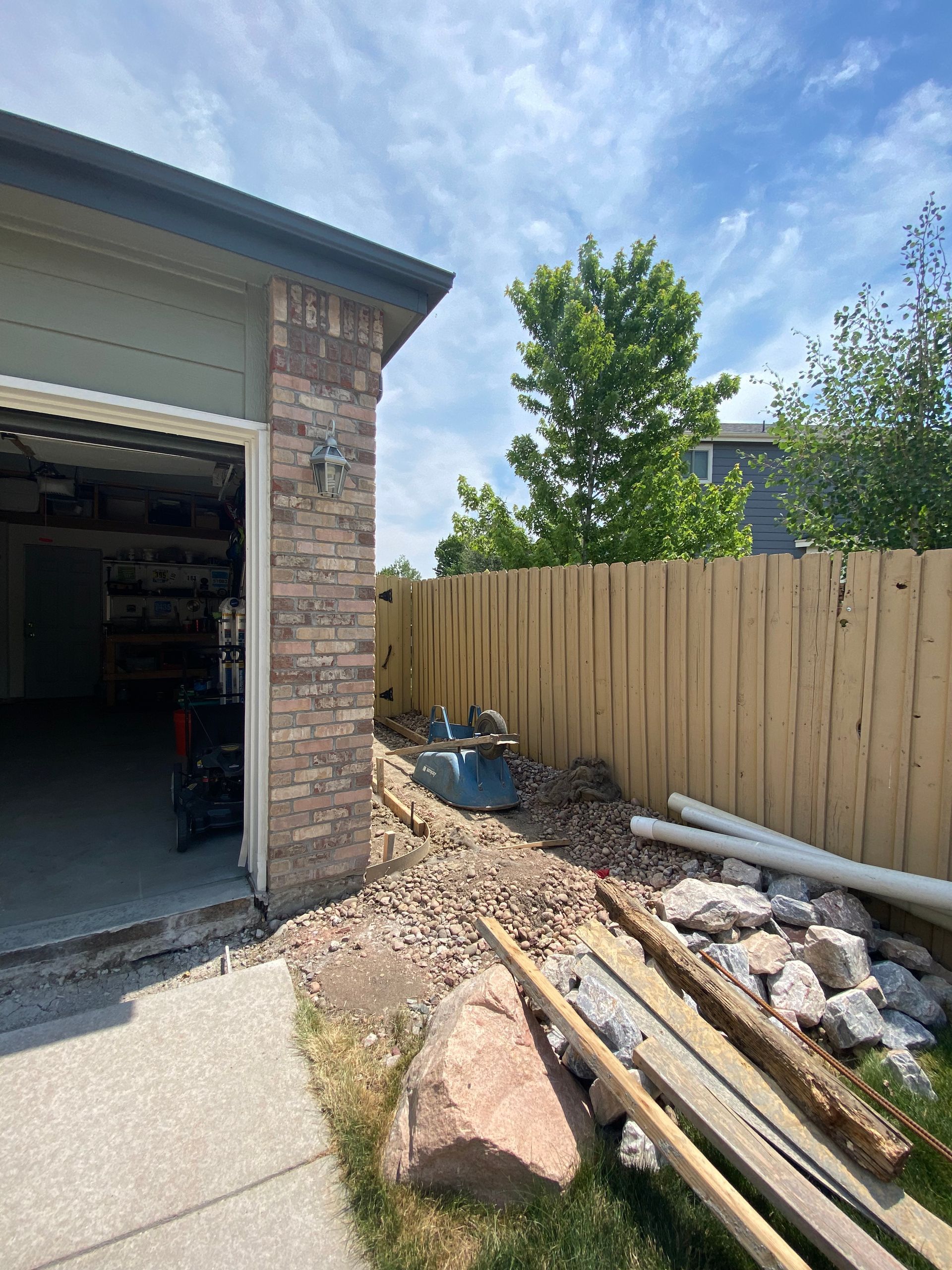 Garage next to a brown fence with landscaping. Construction debris is visible on the ground.