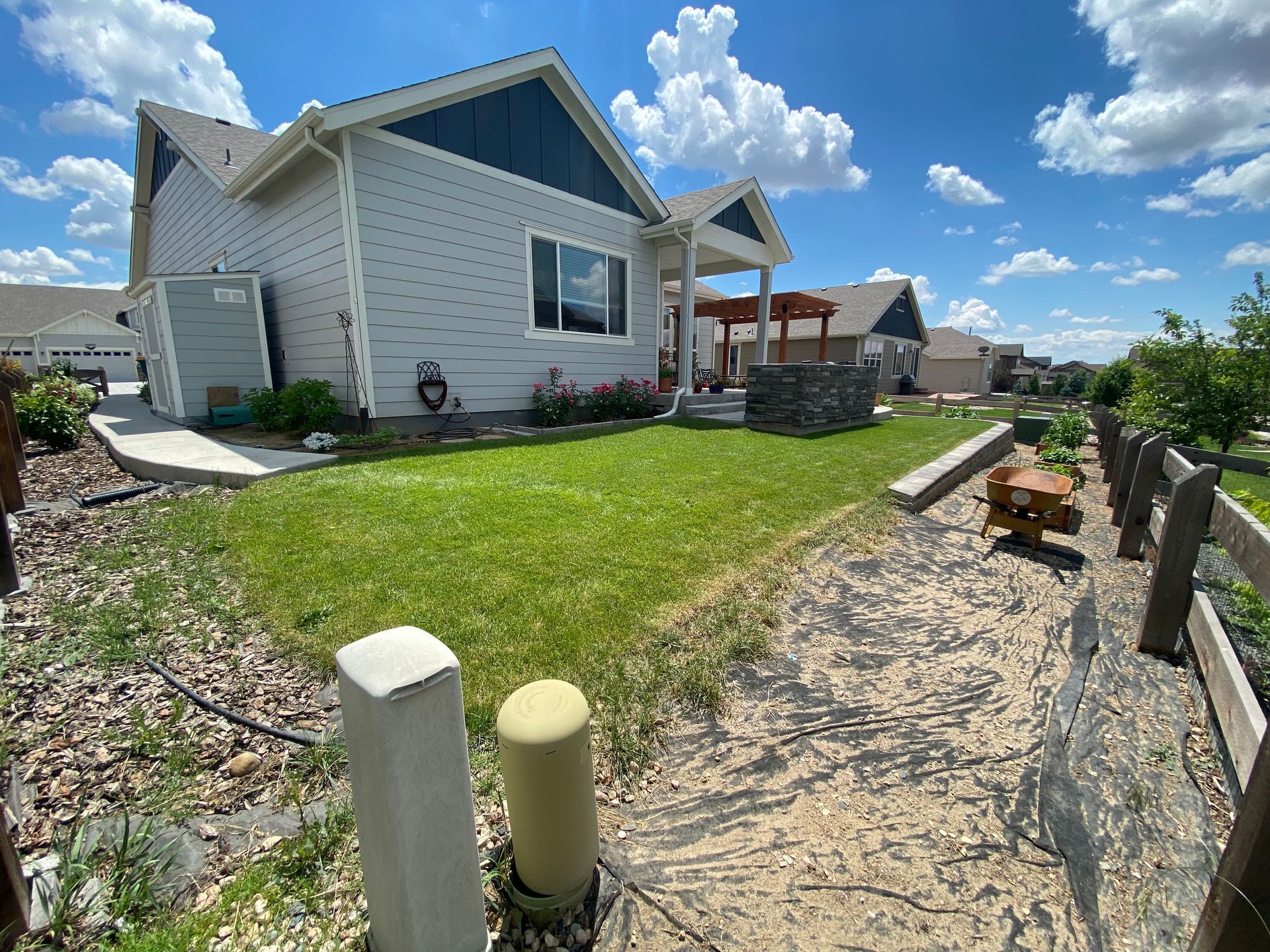 A light blue house with a blue roof and a walkway in the yard on a sunny day.