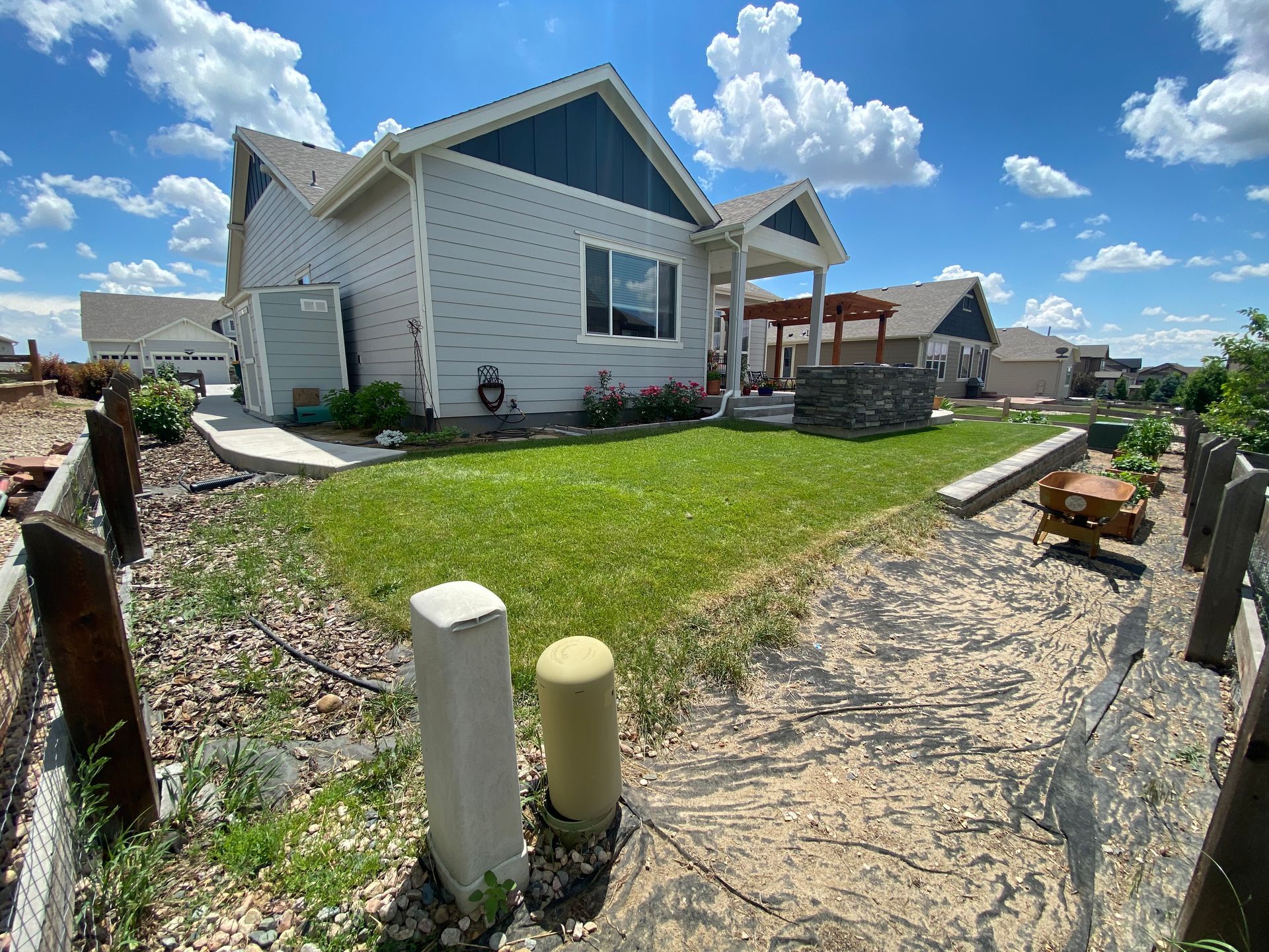 A light-colored house with a blue roof, green lawn, and walkway on a sunny day.