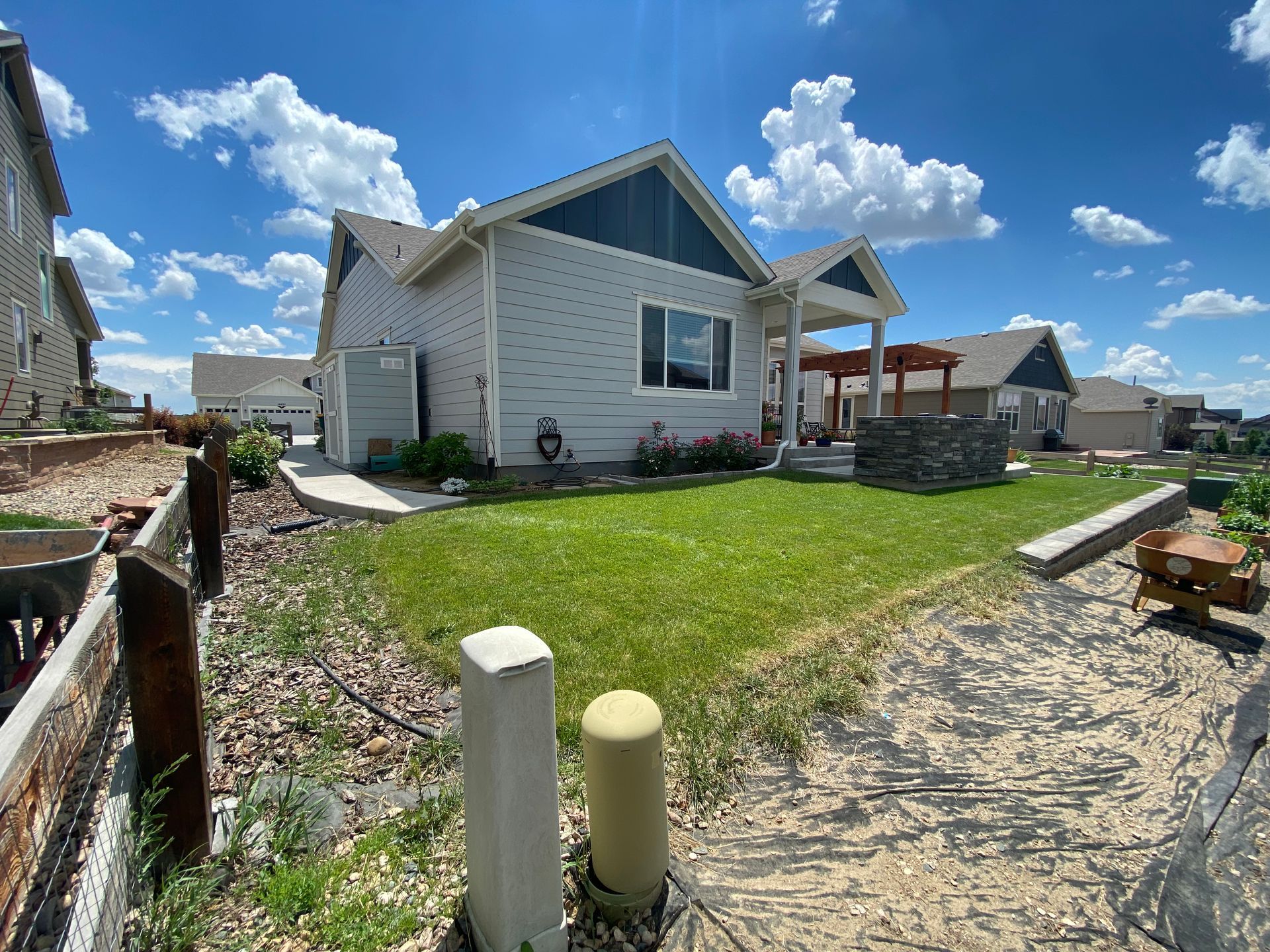Single-story home with blue trim, green lawn, blue sky, and white puffy clouds.
