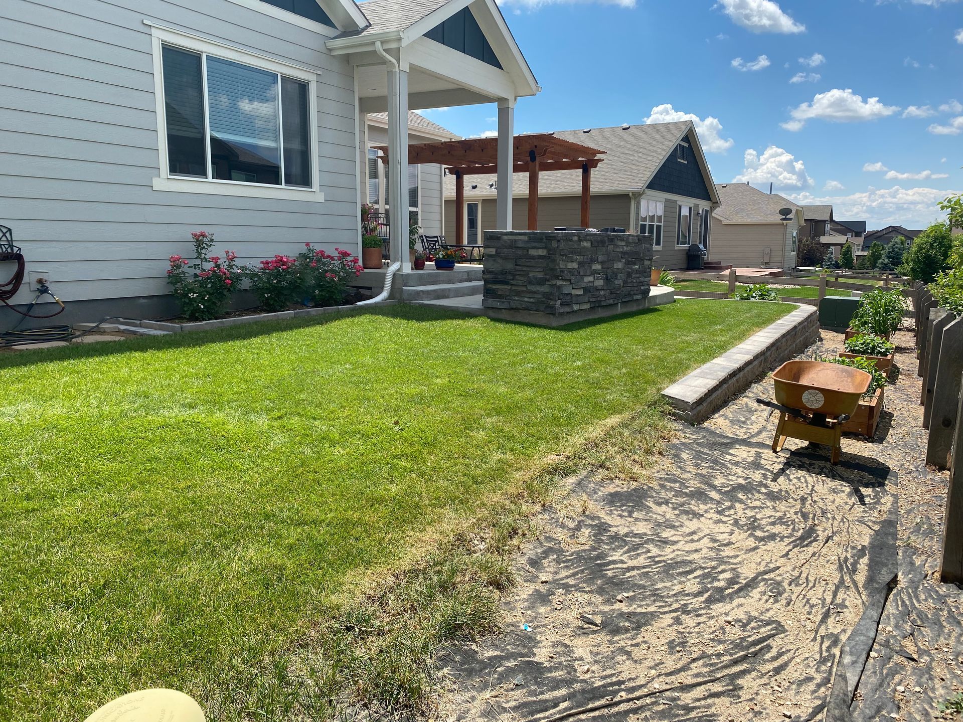 Lawn next to house with stone work and a walkway. Sunny day.