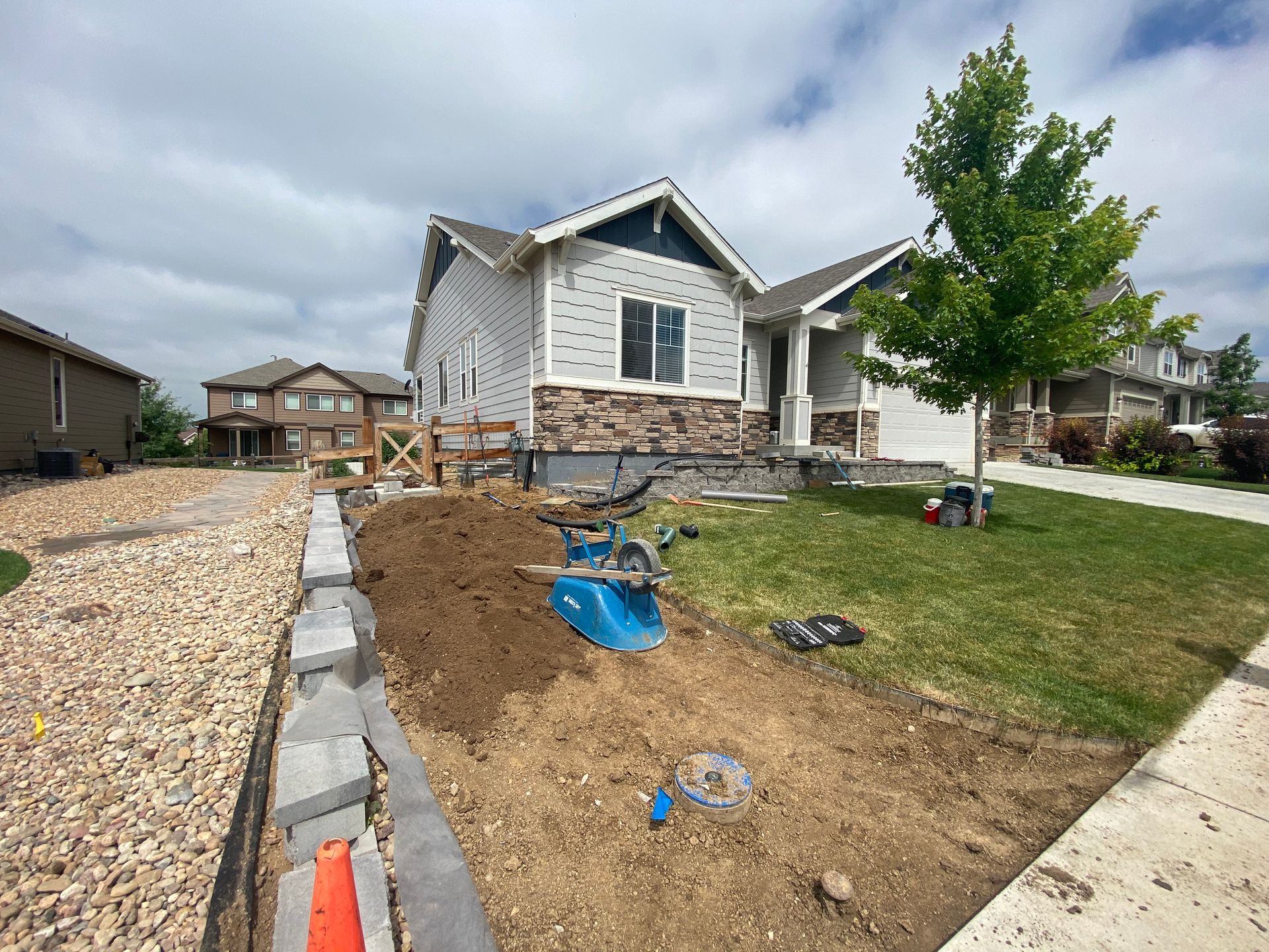 A house under construction with landscaping and a small machine on a dirt pile.