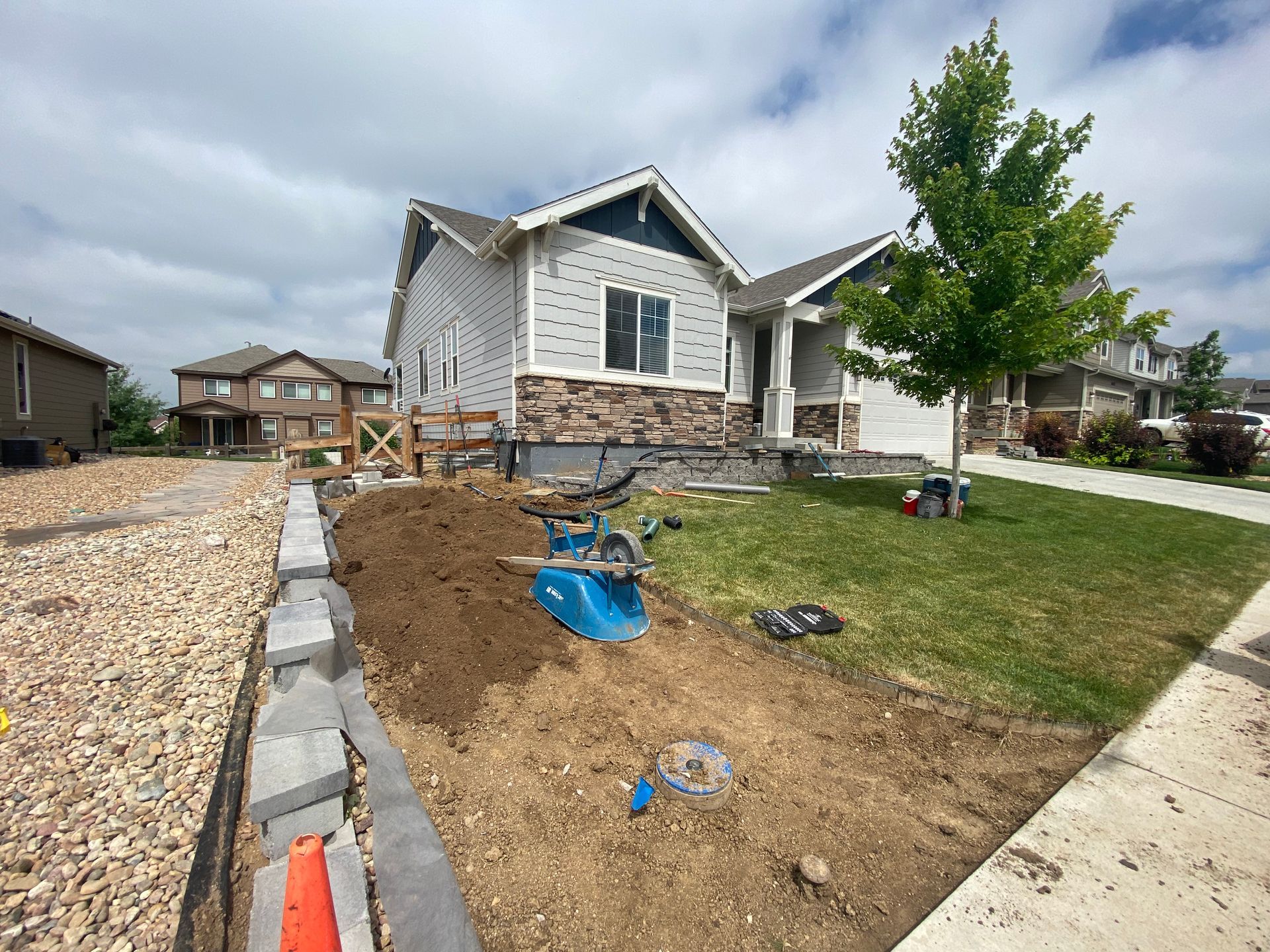 House under construction with landscaping; dirt, blocks, and a small tree in front.