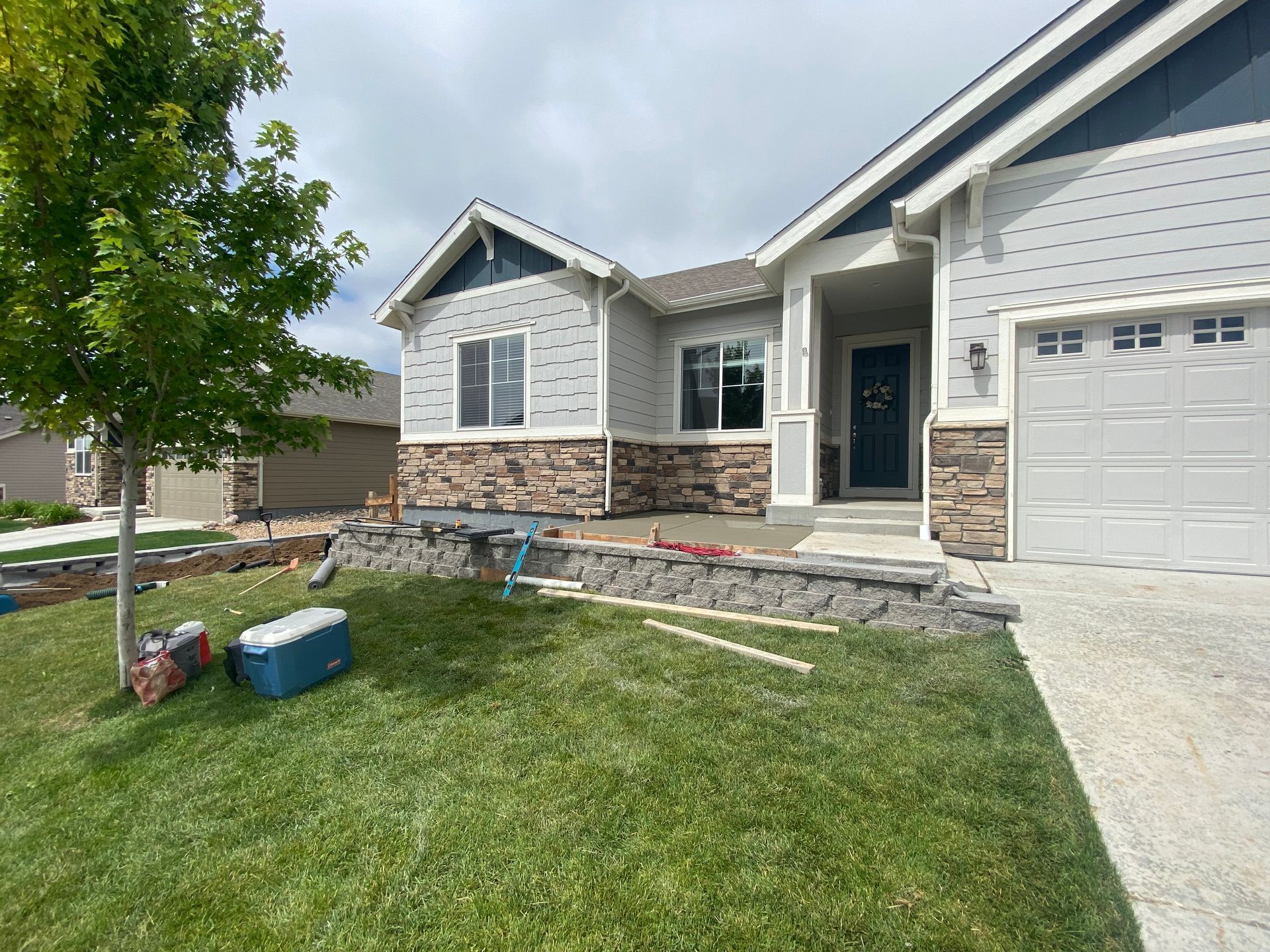 House exterior with light gray siding, stone accents, and front yard landscaping in progress.