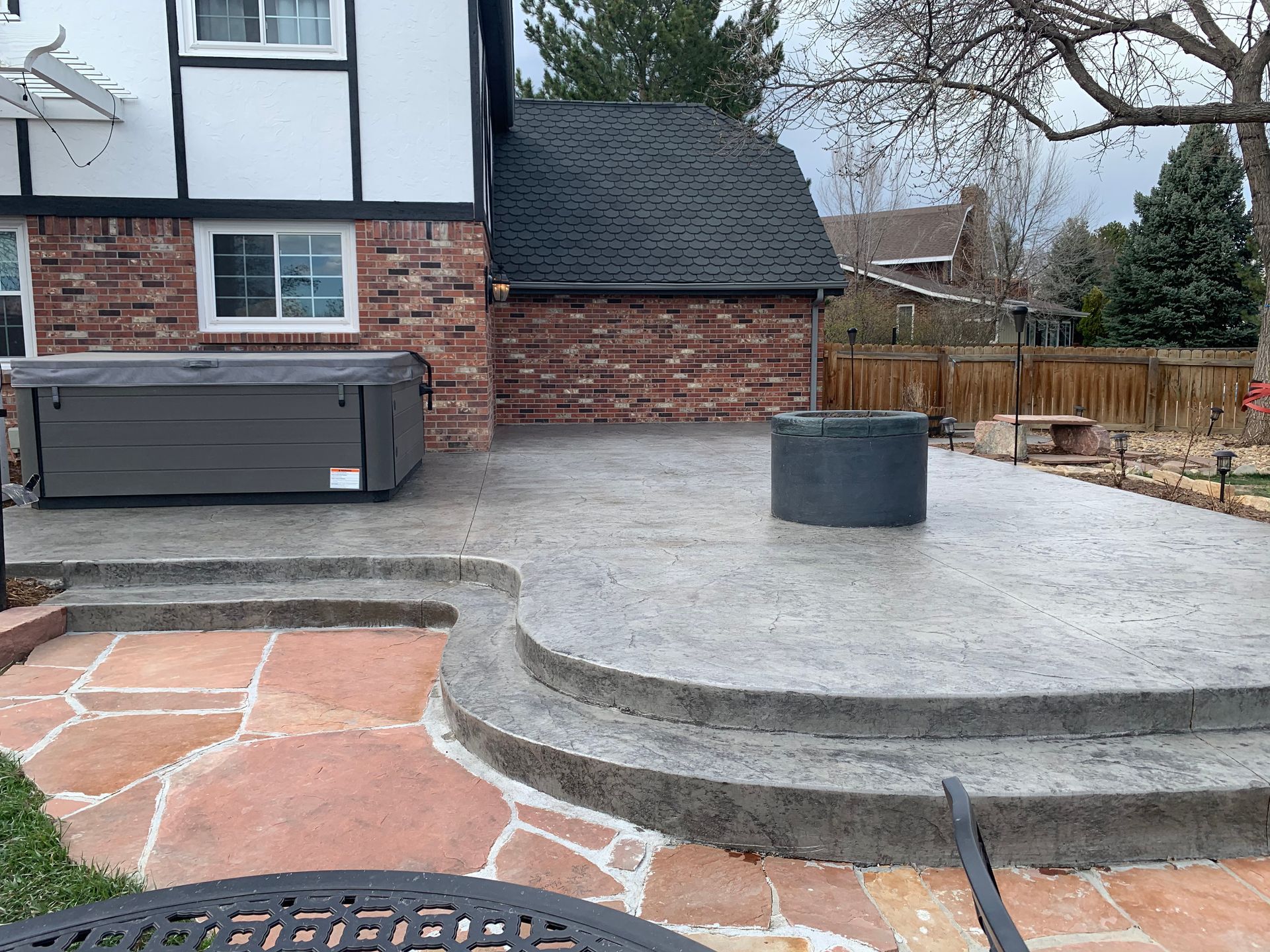 Backyard patio with hot tub, concrete steps, and fire pit.