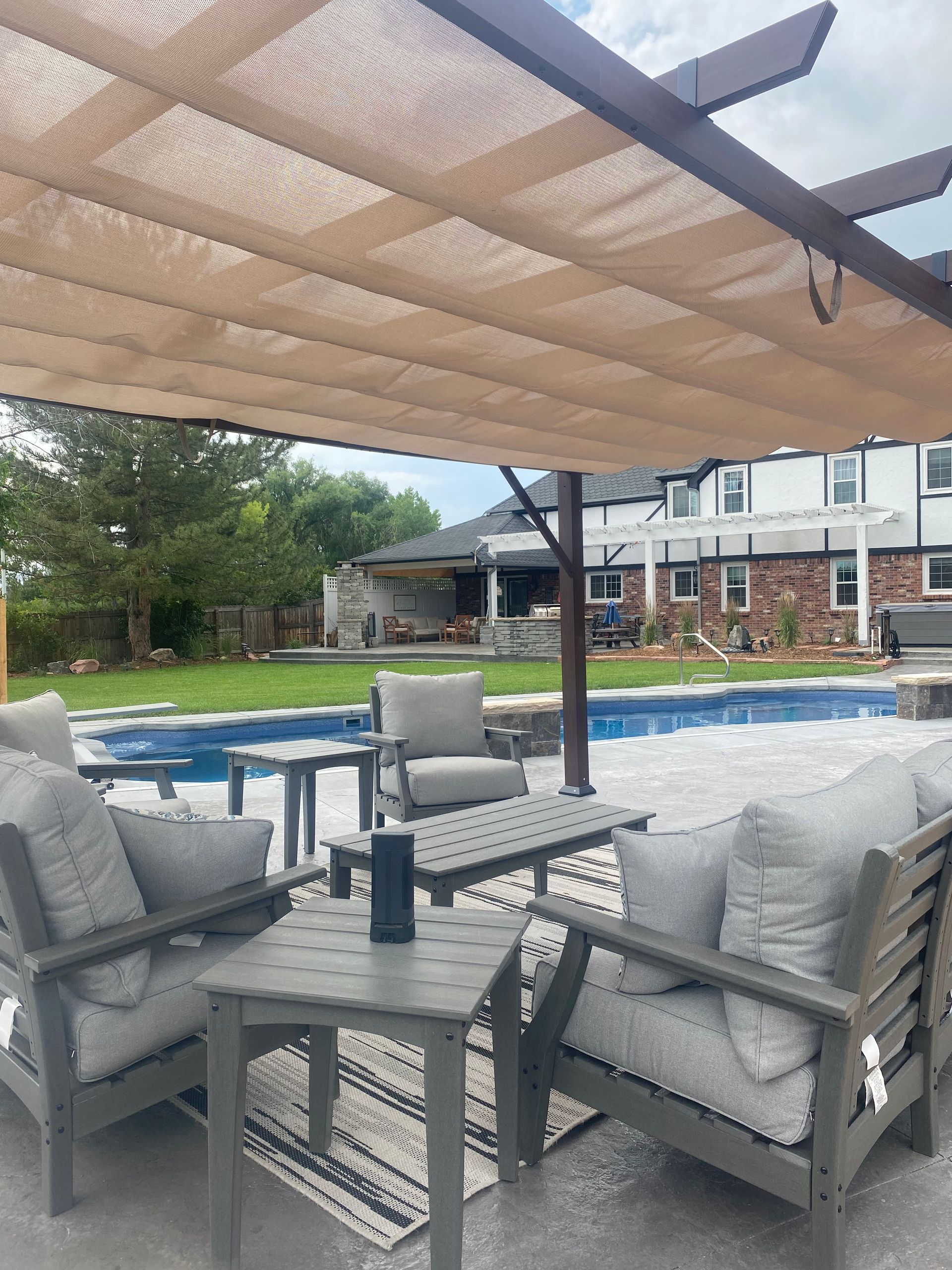 Patio with gray furniture, a pergola with a sunshade, and a swimming pool.