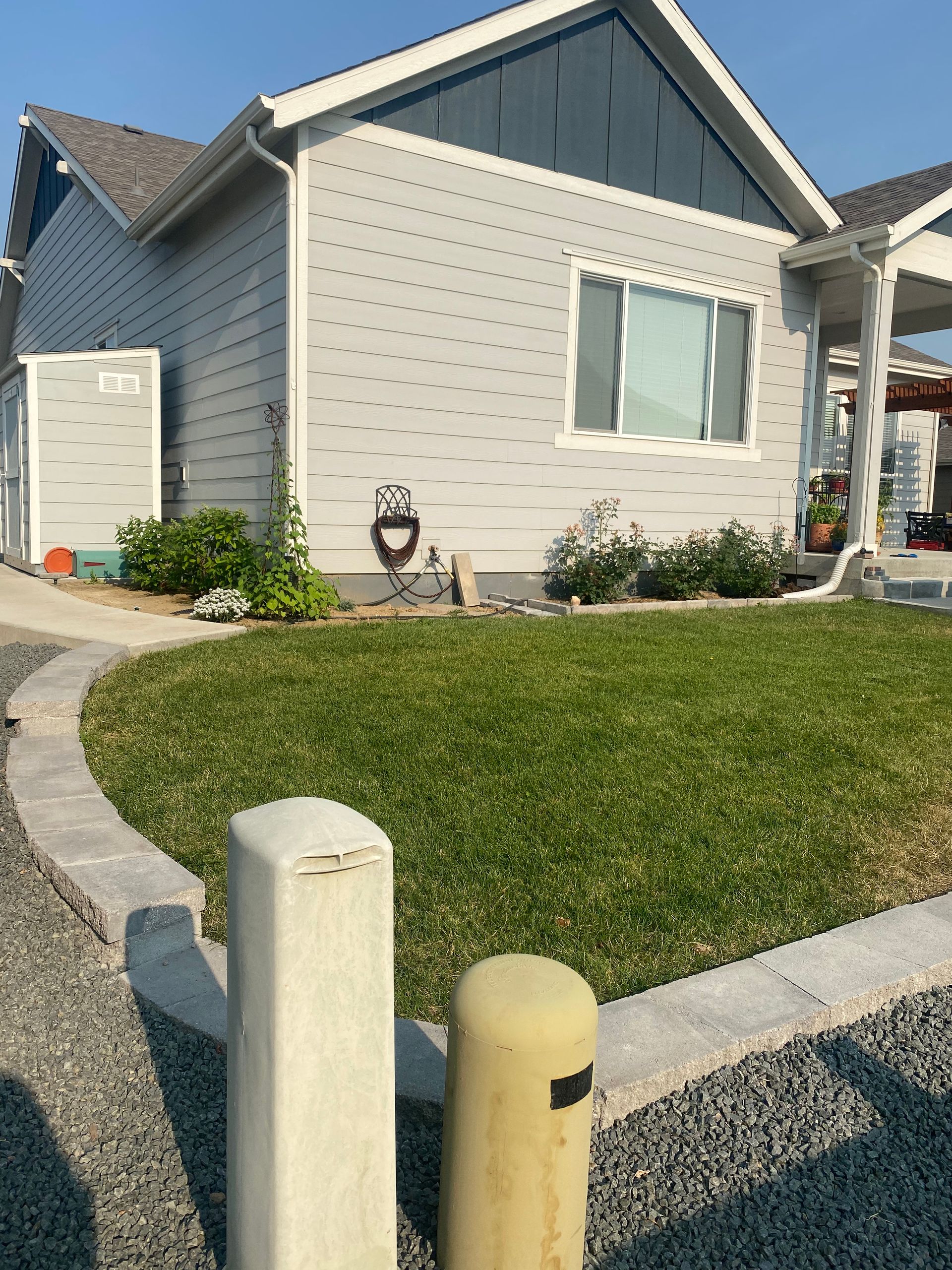 A light blue house with a well-manicured lawn and a gray gravel border.