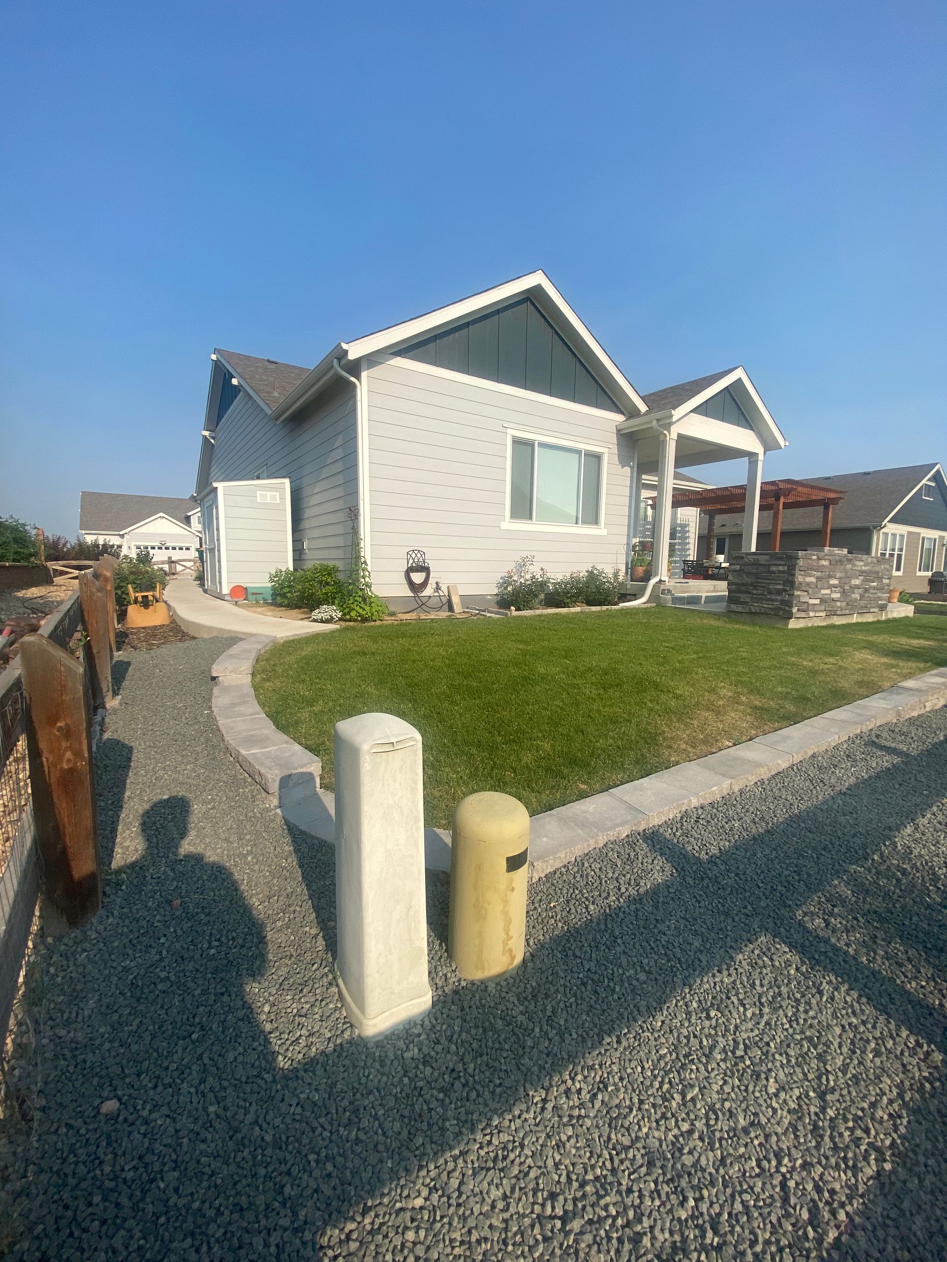 A light blue house with a gray roof and a well-manicured lawn. A gravel path leads to the front door.