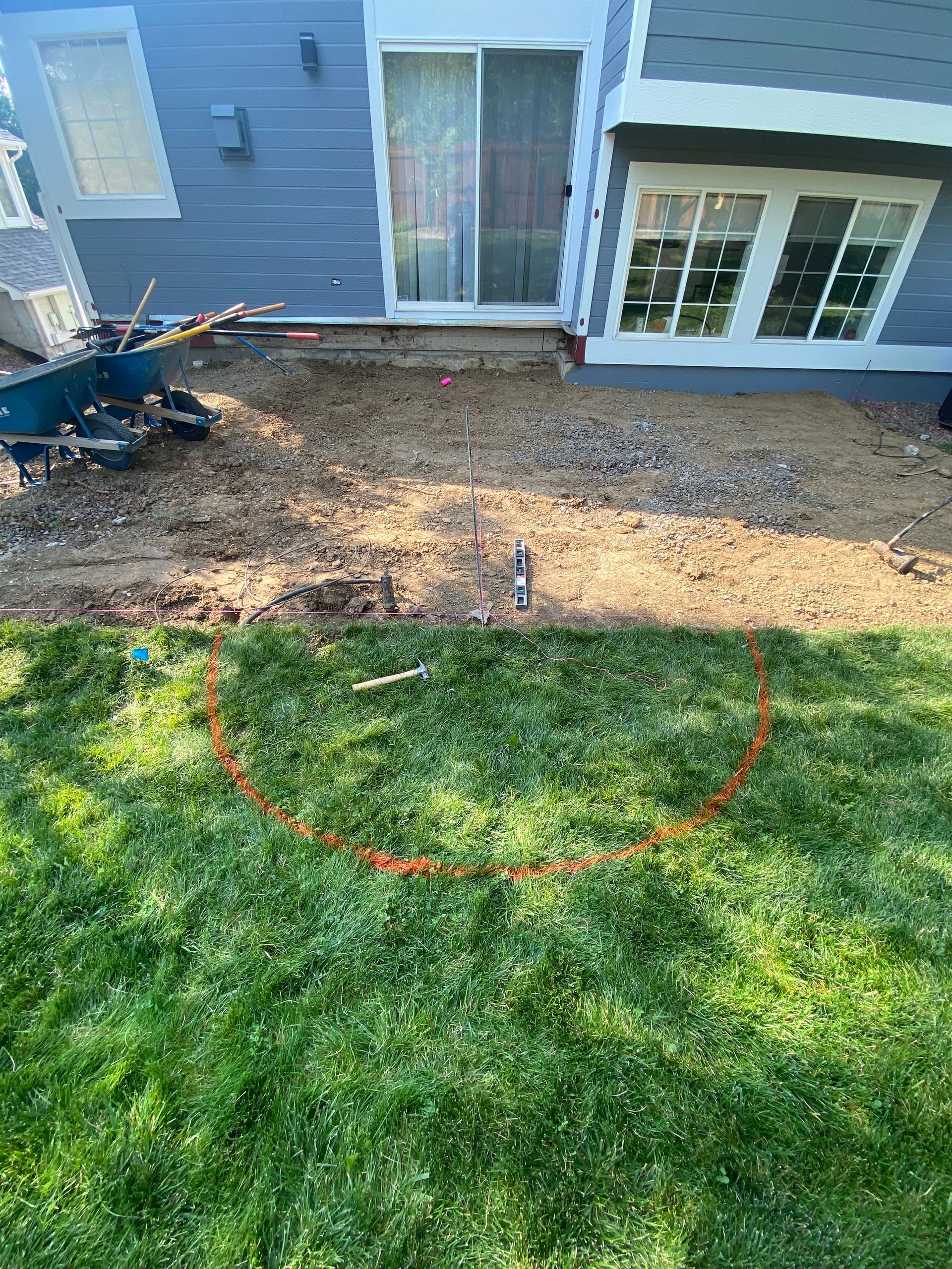 Backyard with gravel bed near a house and a lawn with a red curved line.