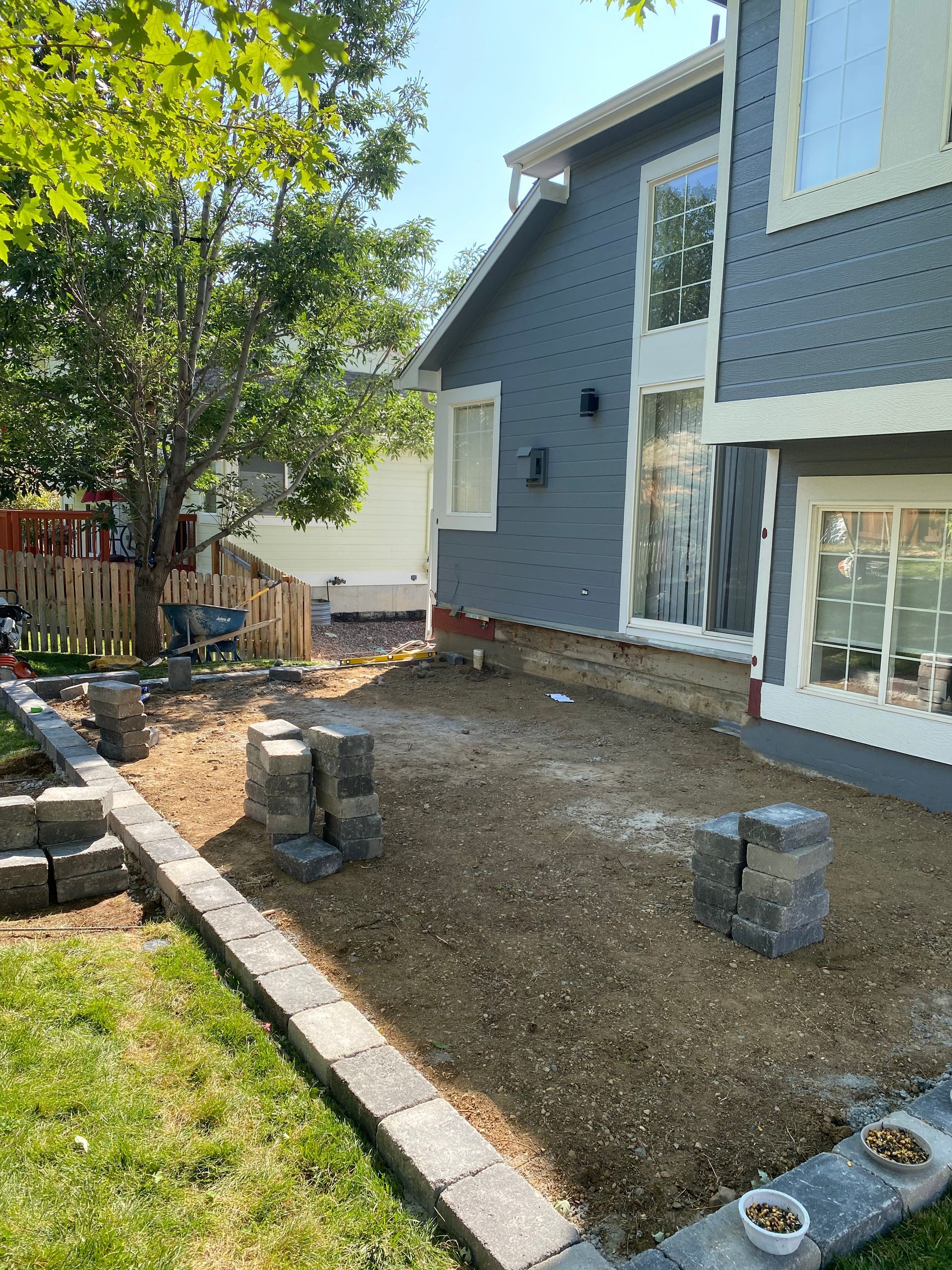 Backyard with a raised stone border and gravel base near a blue house.
