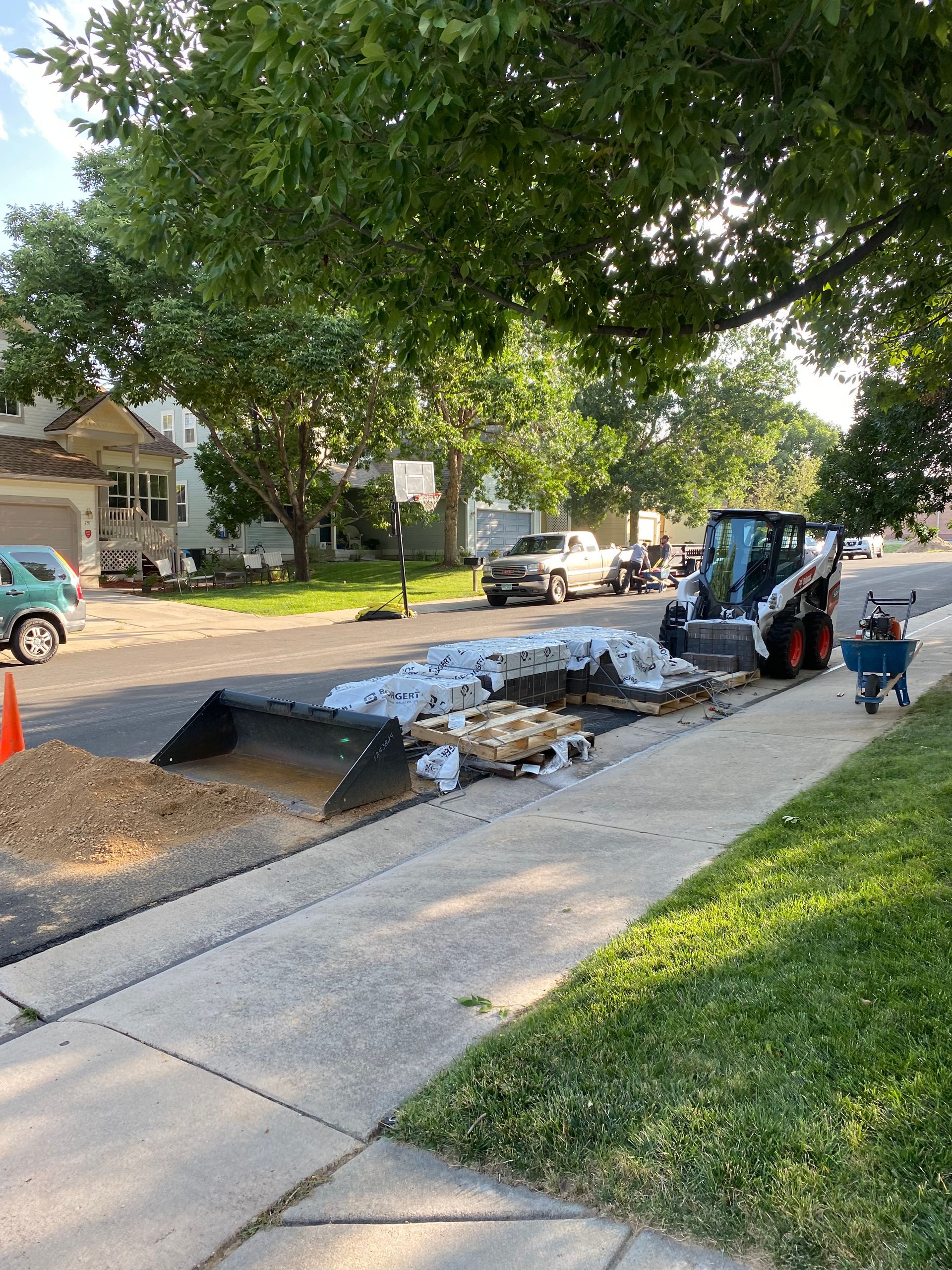 Road construction on a residential street; a small tractor, bags, and tools are visible.