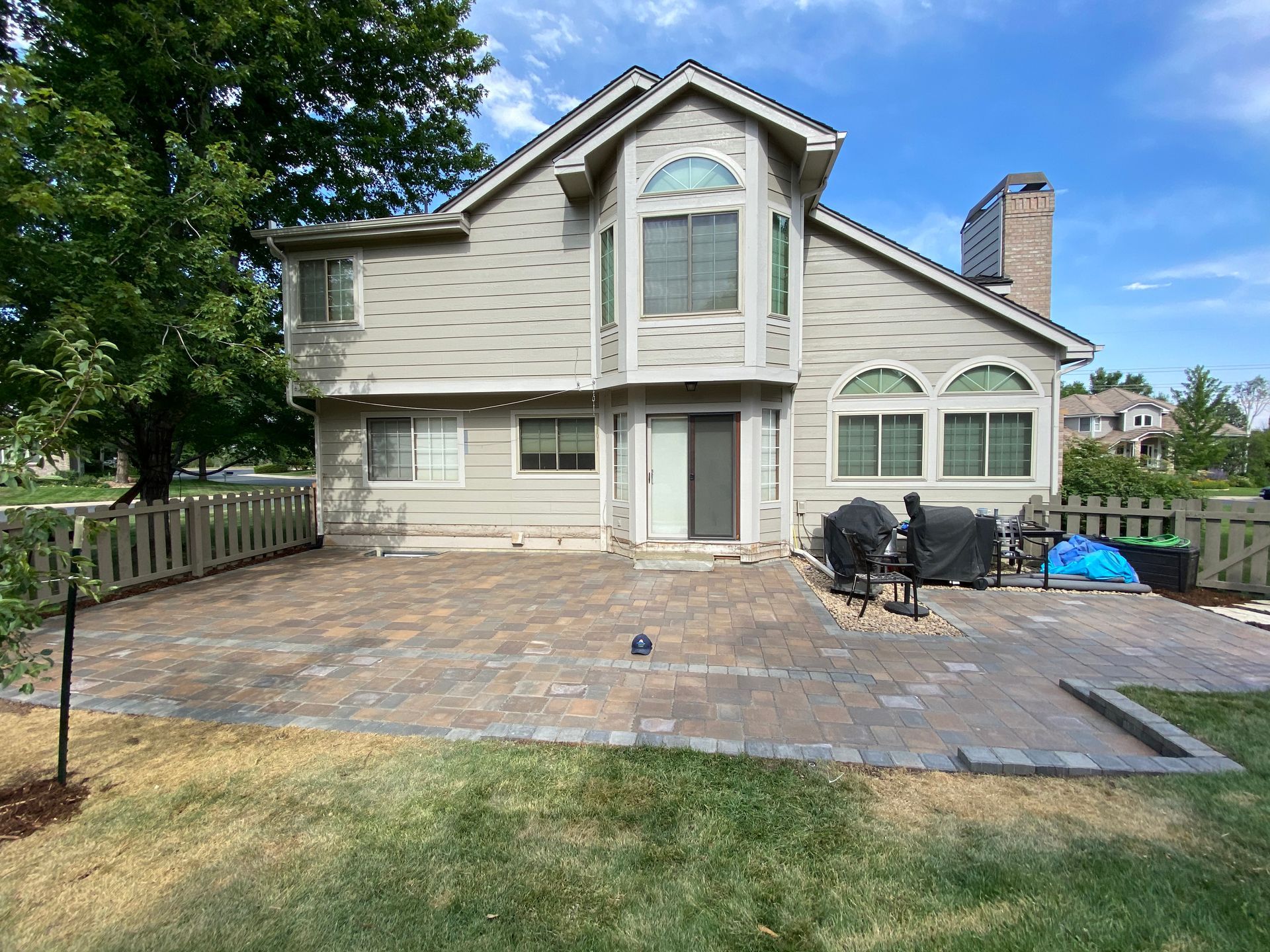 Backyard patio with a house, brick pavers, and some landscaping.