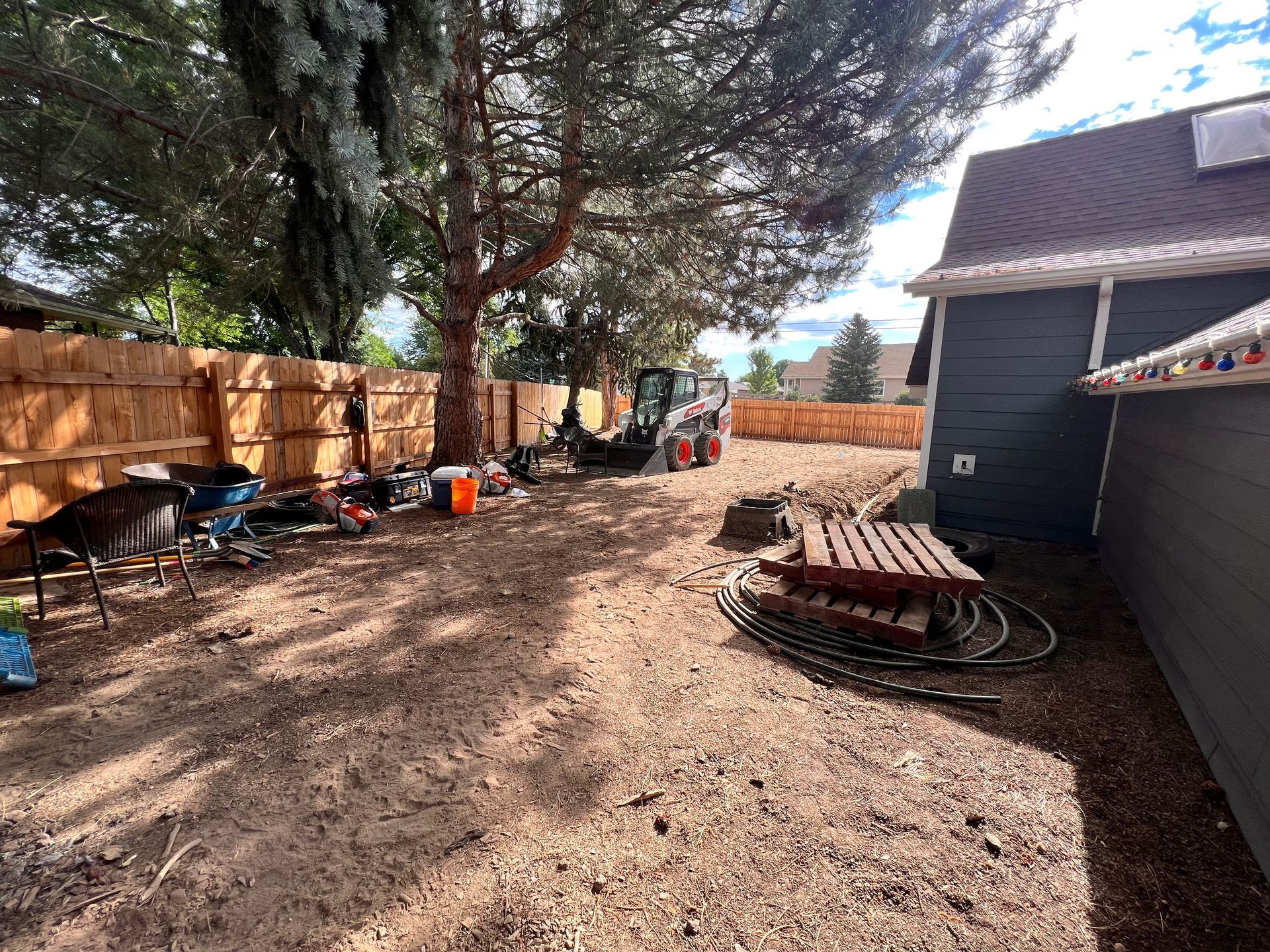 Backyard with a brown fence, tools, a small tractor, and a picnic table.
