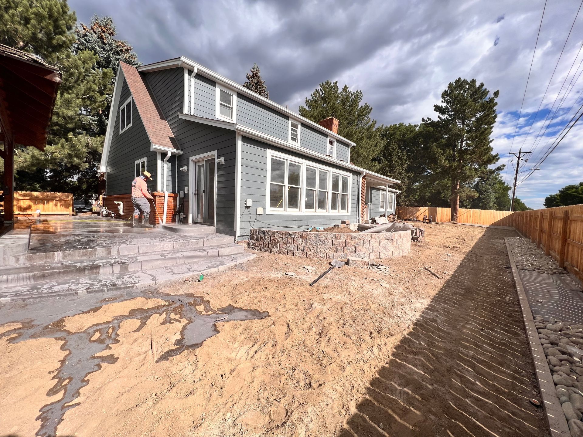 Two-story blue house under a cloudy sky, with construction in progress in the yard.