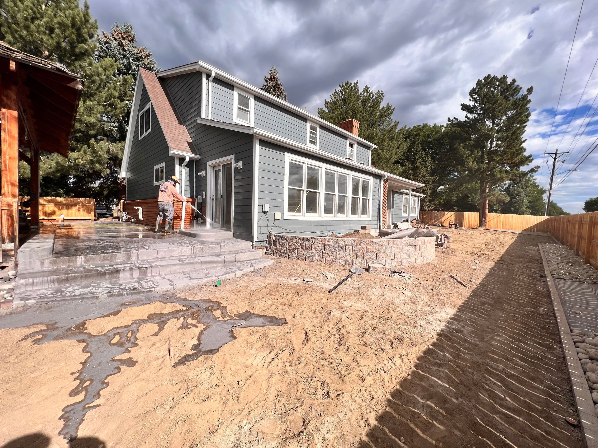 A two-story blue house with construction in progress; a person is on the porch.
