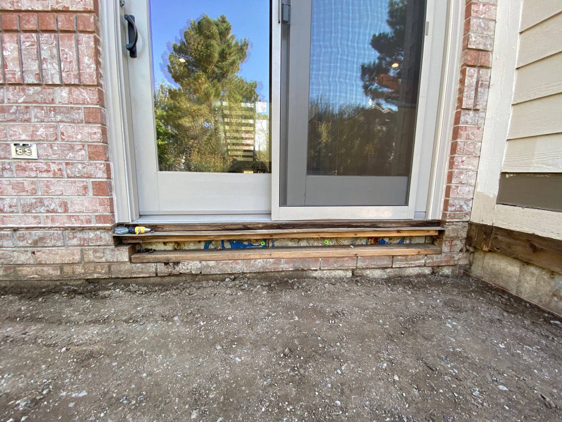 Exterior doorway with exposed wooden threshold and brickwork.