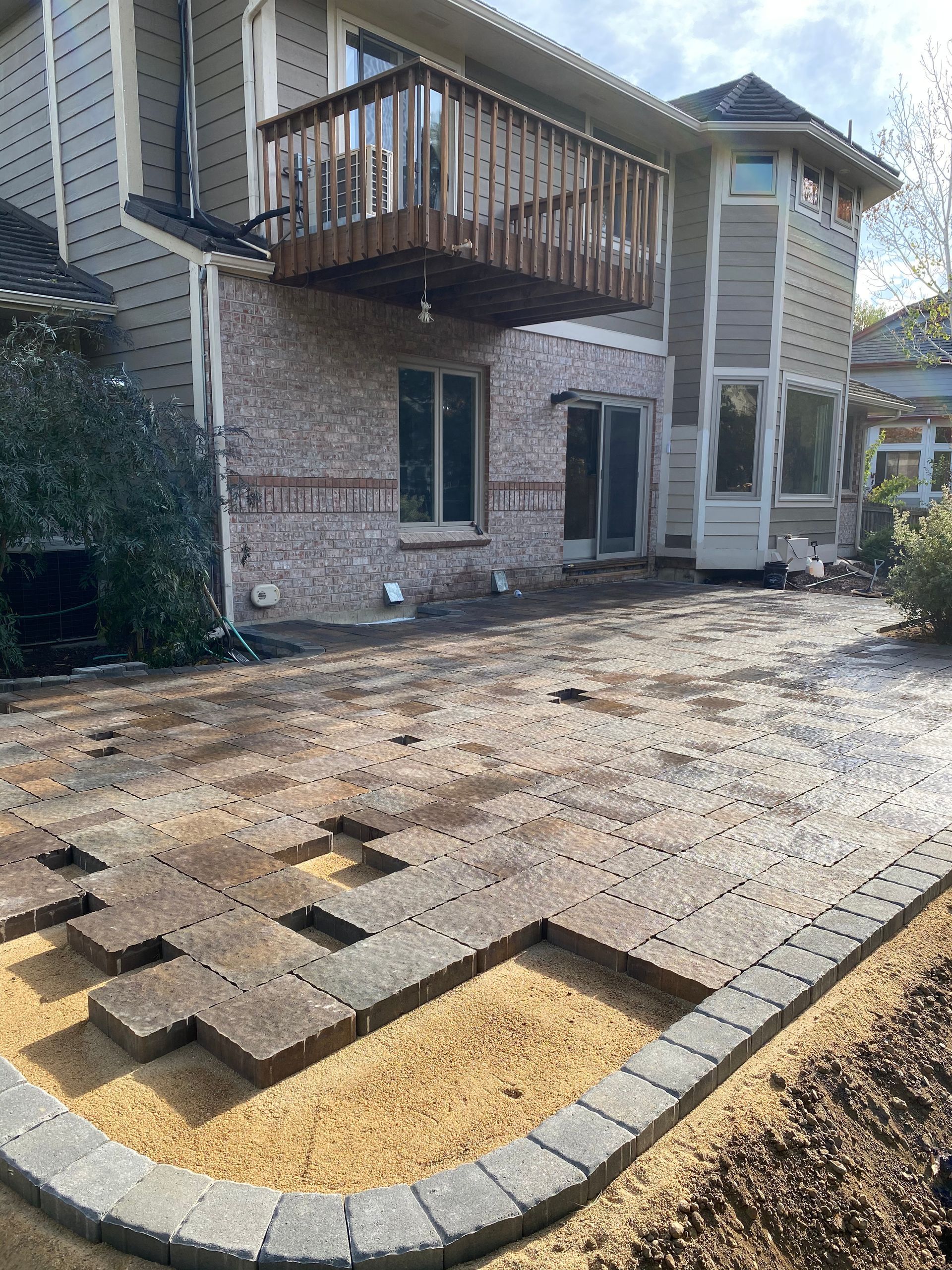 Backyard patio construction with brick pavers and raised deck.