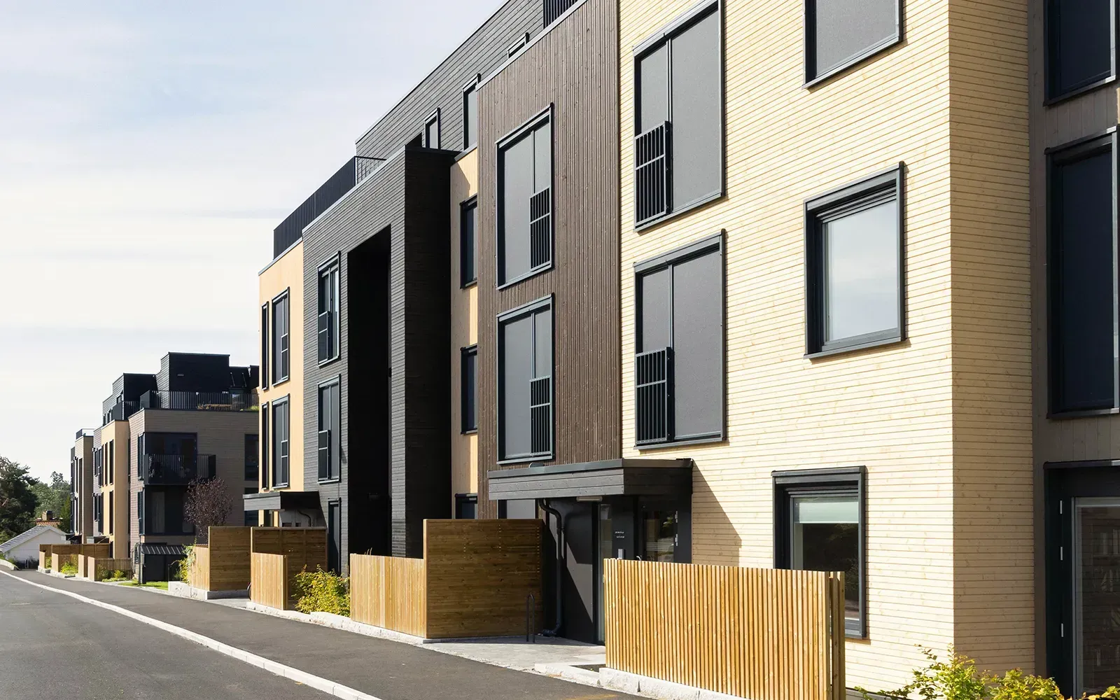 Fasadeutsnitt i Østensjøporten med beige, brun og svart trekledning, store vinduer og moderne inngangsparti