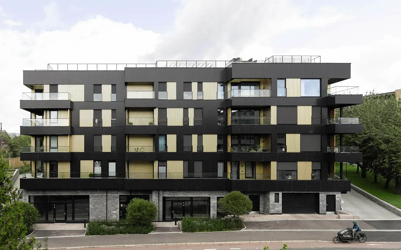 Boligbygg på Tøyentaket i Ensjøveien med svarte og gule fasadeplater, store vinduer og inntrukne balkonger