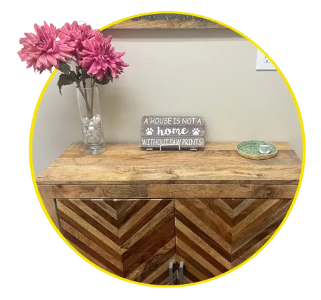 Wooden sign on a rustic table reads “A house is not a home without cat paw prints” with flowers nearby