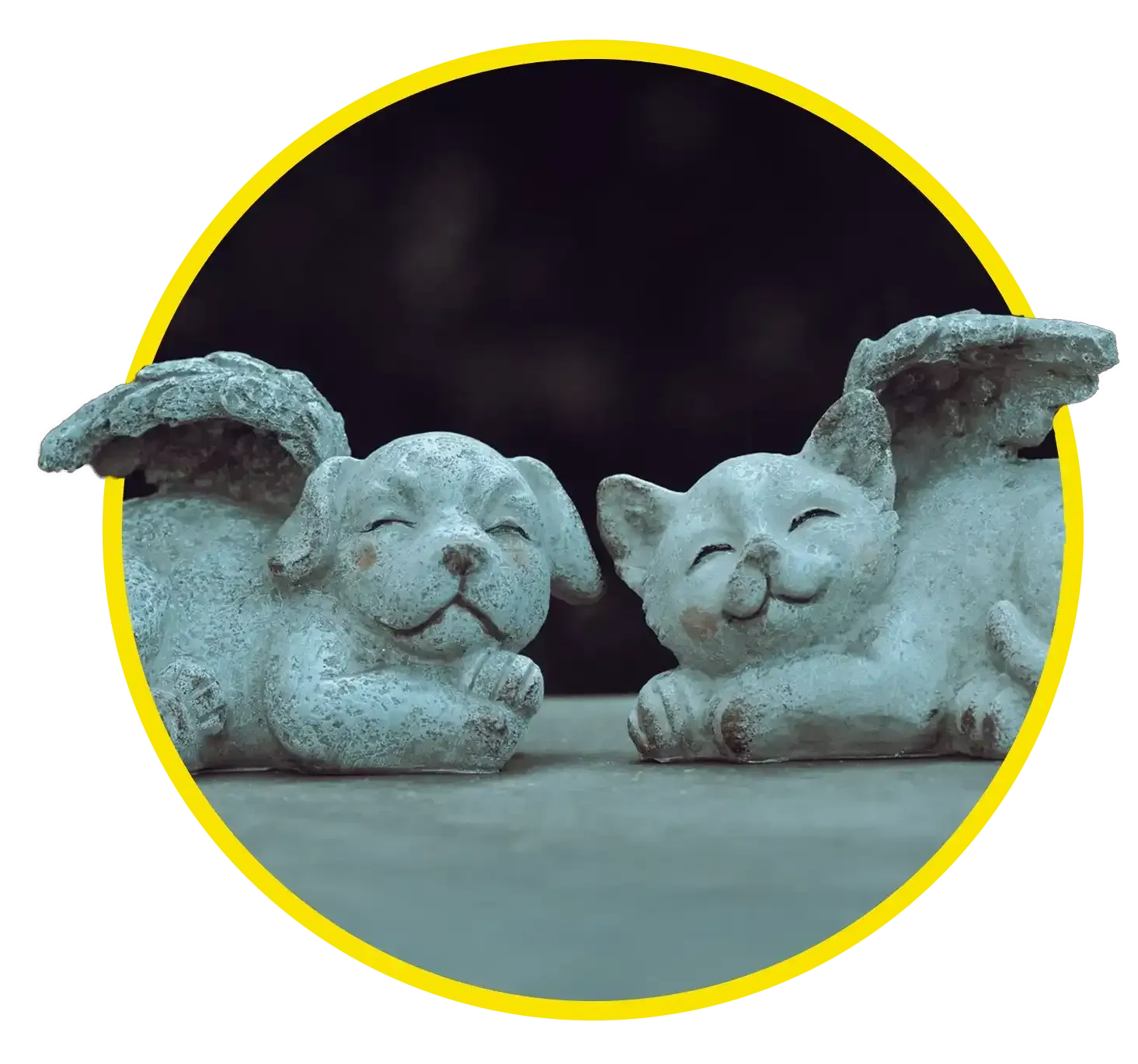 Two small stone angel pet figurines sleeping side by side on a dark surface