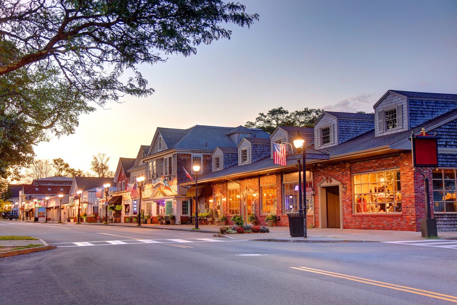 Street with shops, streetlights, and buildings at dusk.