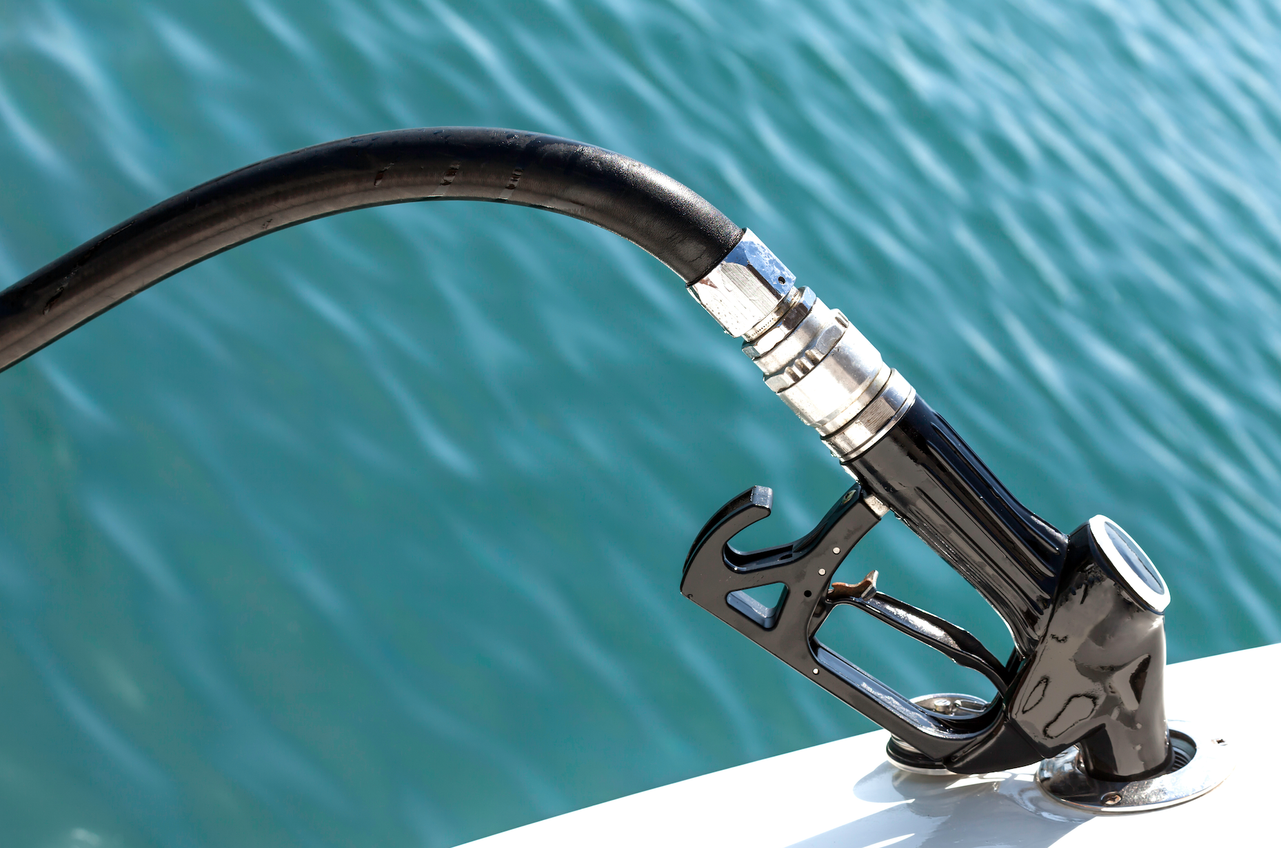 A man is washing a boat with a hose on a dock.