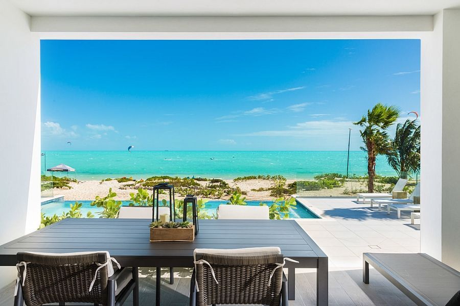 Oceanfront patio with table and chairs overlooking a bright turquoise beach and sea