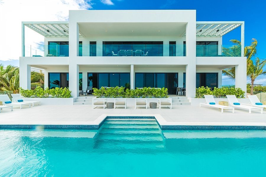 Modern white beachfront villa with a turquoise pool and ocean view