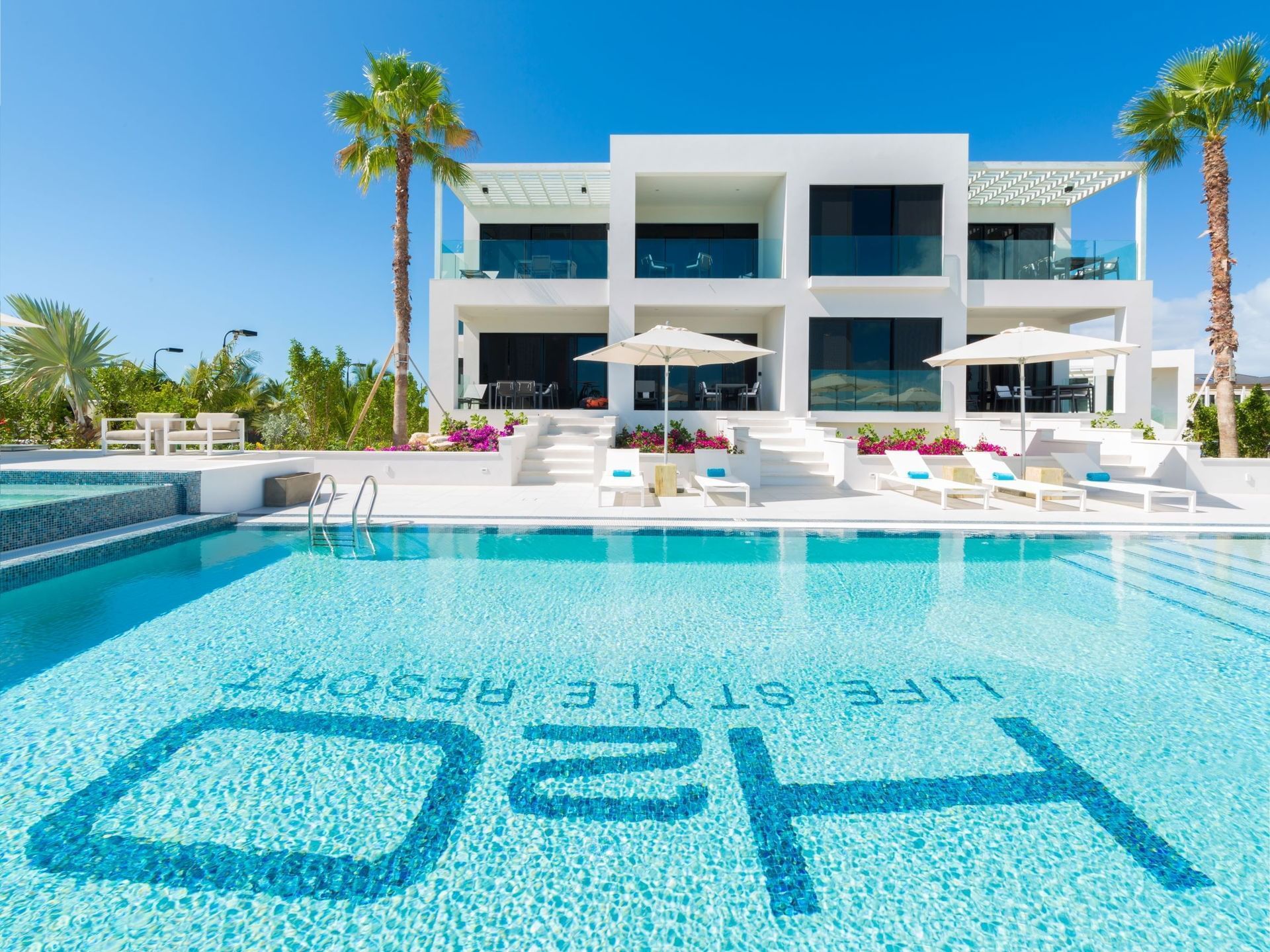 Luxury resort pool with blue water and modern white villas under palm trees