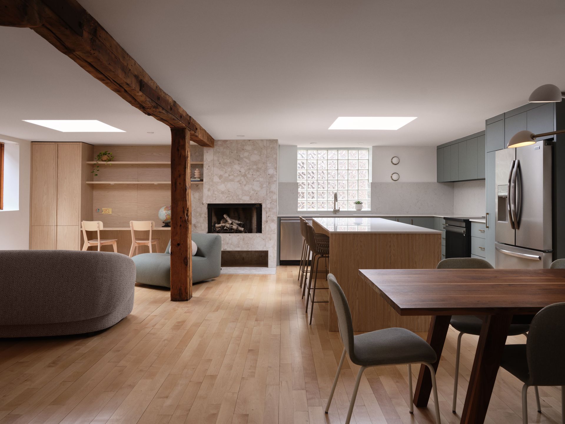 Cuisine/séjour ouverte avec parquet, cheminée et meubles modernes. Table à manger avec chaises ; îlot central avec tabourets.