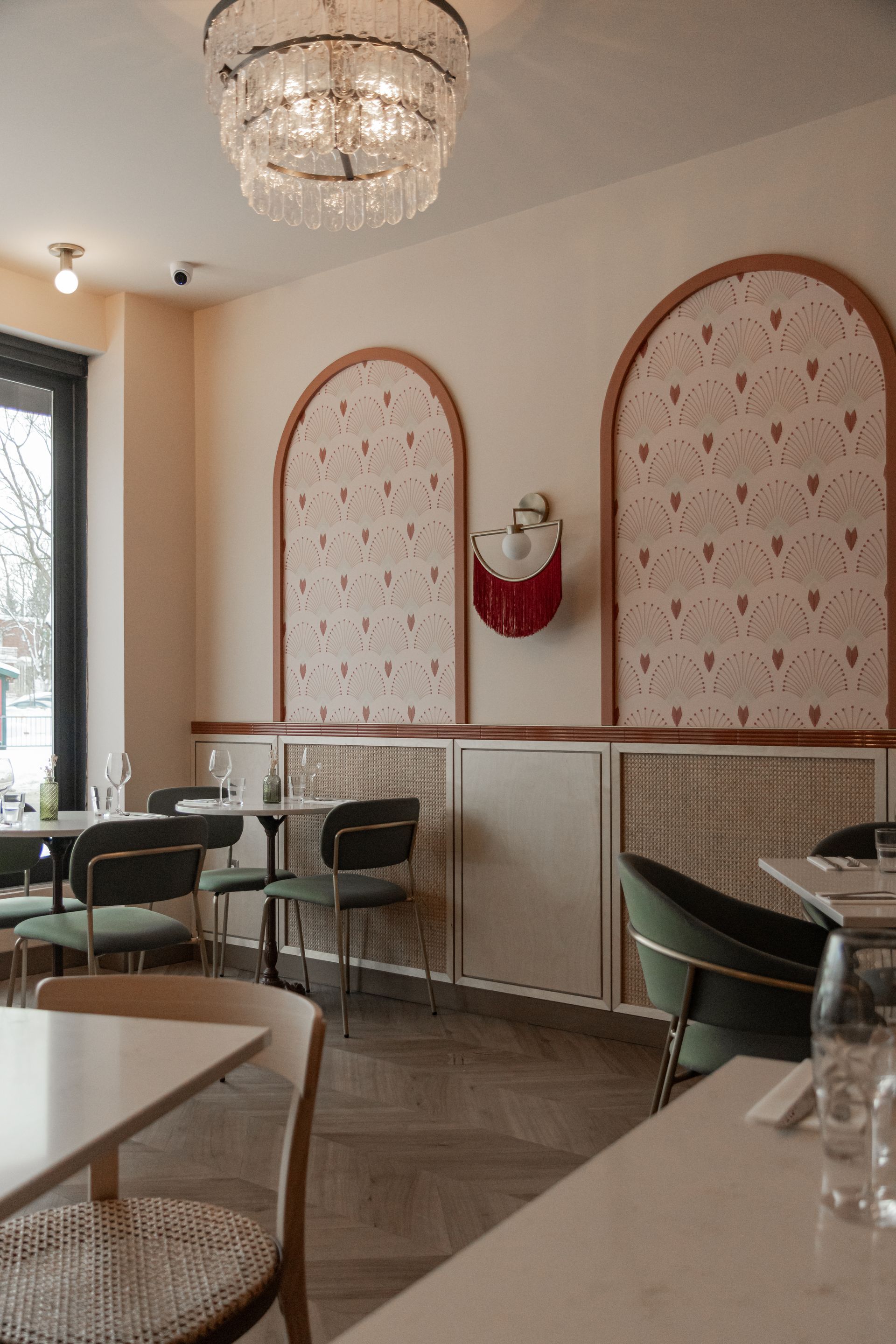 Intérieur élégant de ce café, avec des panneaux muraux arqués, des chaises vertes et un lustre.