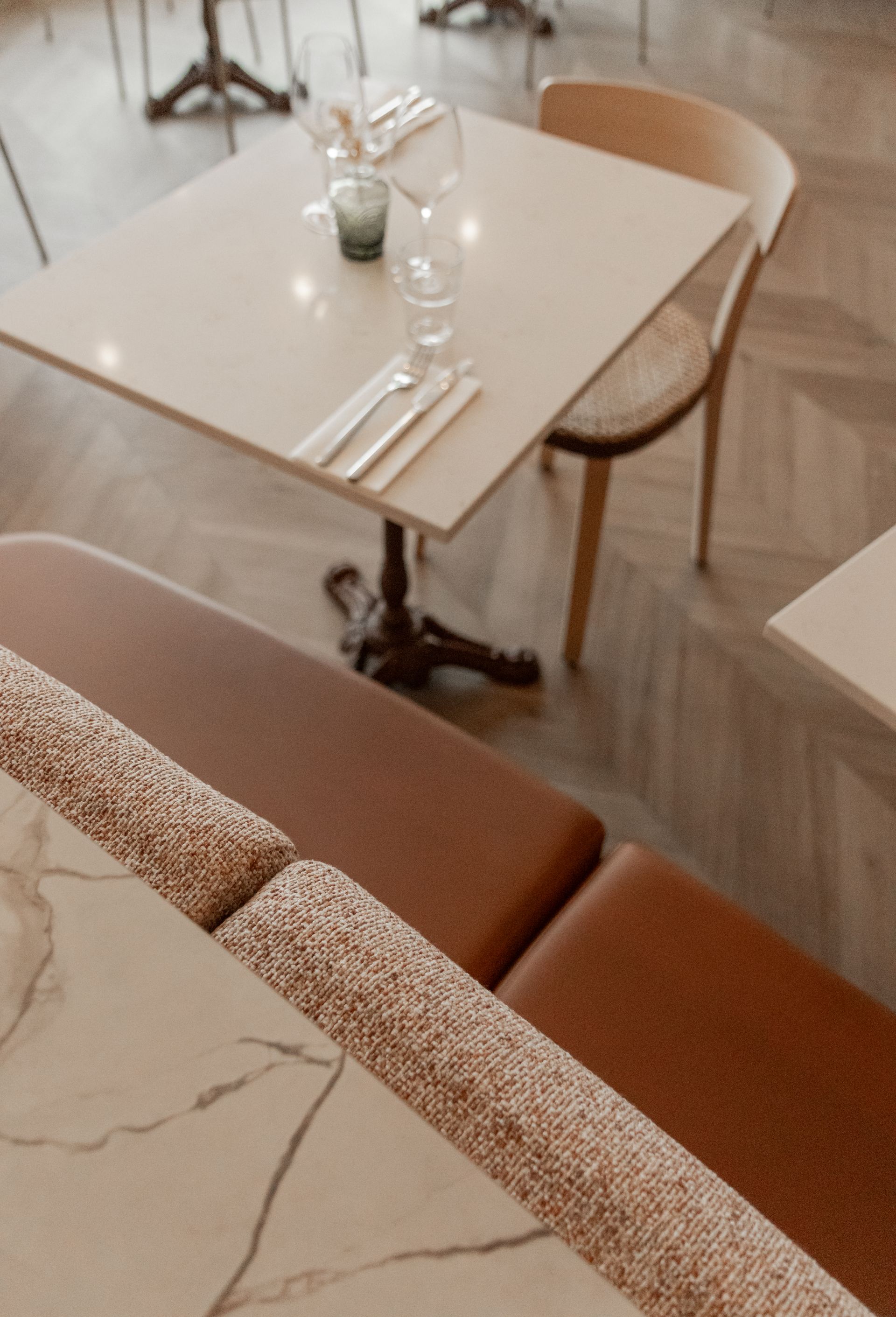 Table de café confortable avec verres et couverts à côté d'une chaise rembourrée marron et d'un parquet clair